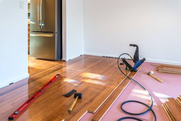 Hardwood floor installation in modern home with tools and pneumatic nailer on unfinished surface.