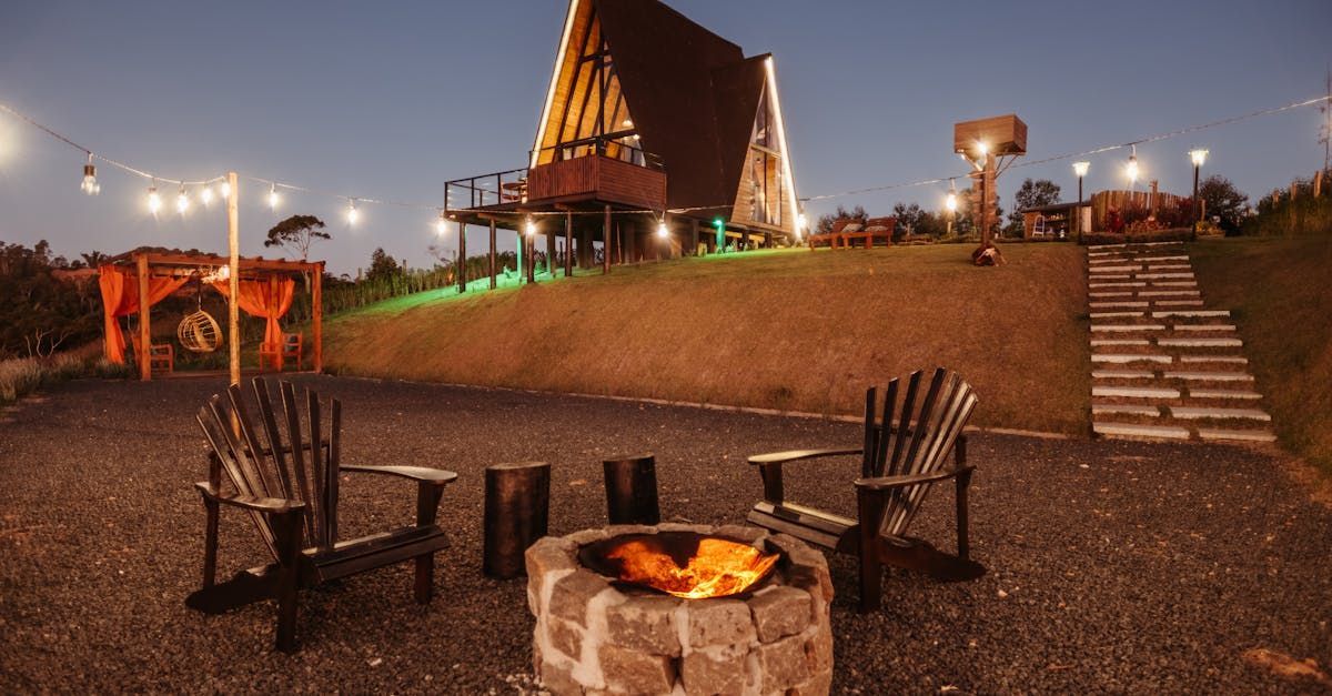 A fire pit with chairs around it in front of a cabin at night.