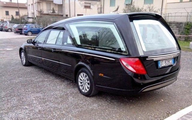 carro funebre con composizioni floreali all'interno