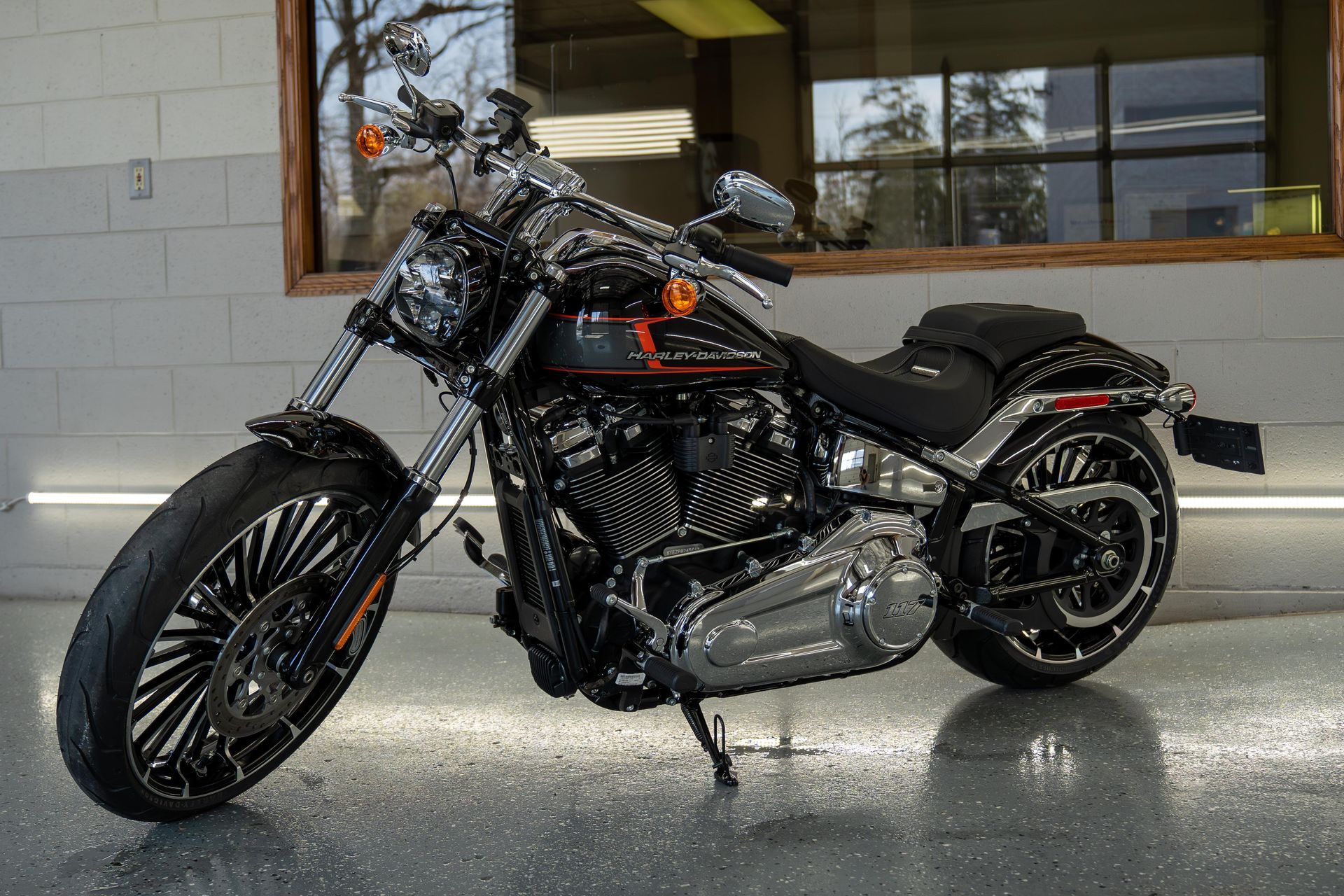A harley davidson motorcycle is parked in a garage in front of a window.