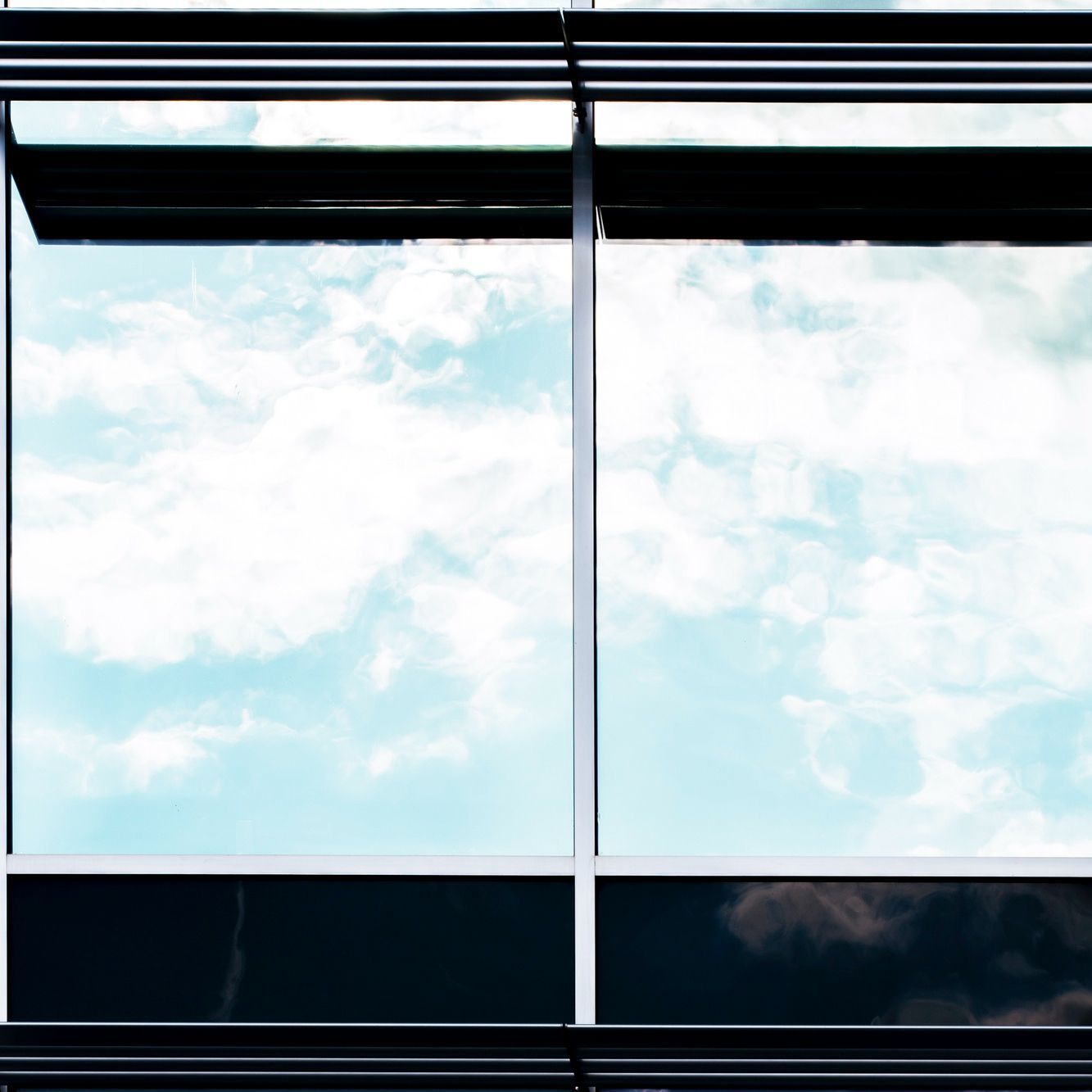 A building with a lot of windows and a blue sky reflected in the windows.