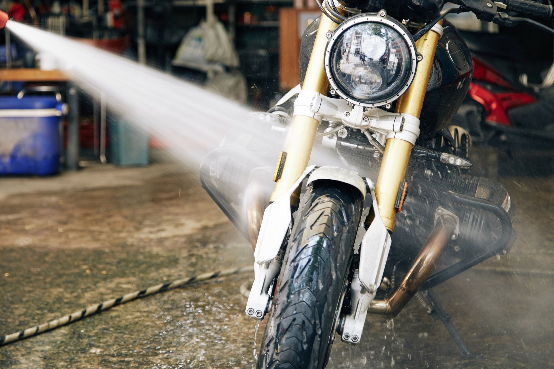 A person is washing a motorcycle with a high pressure washer.