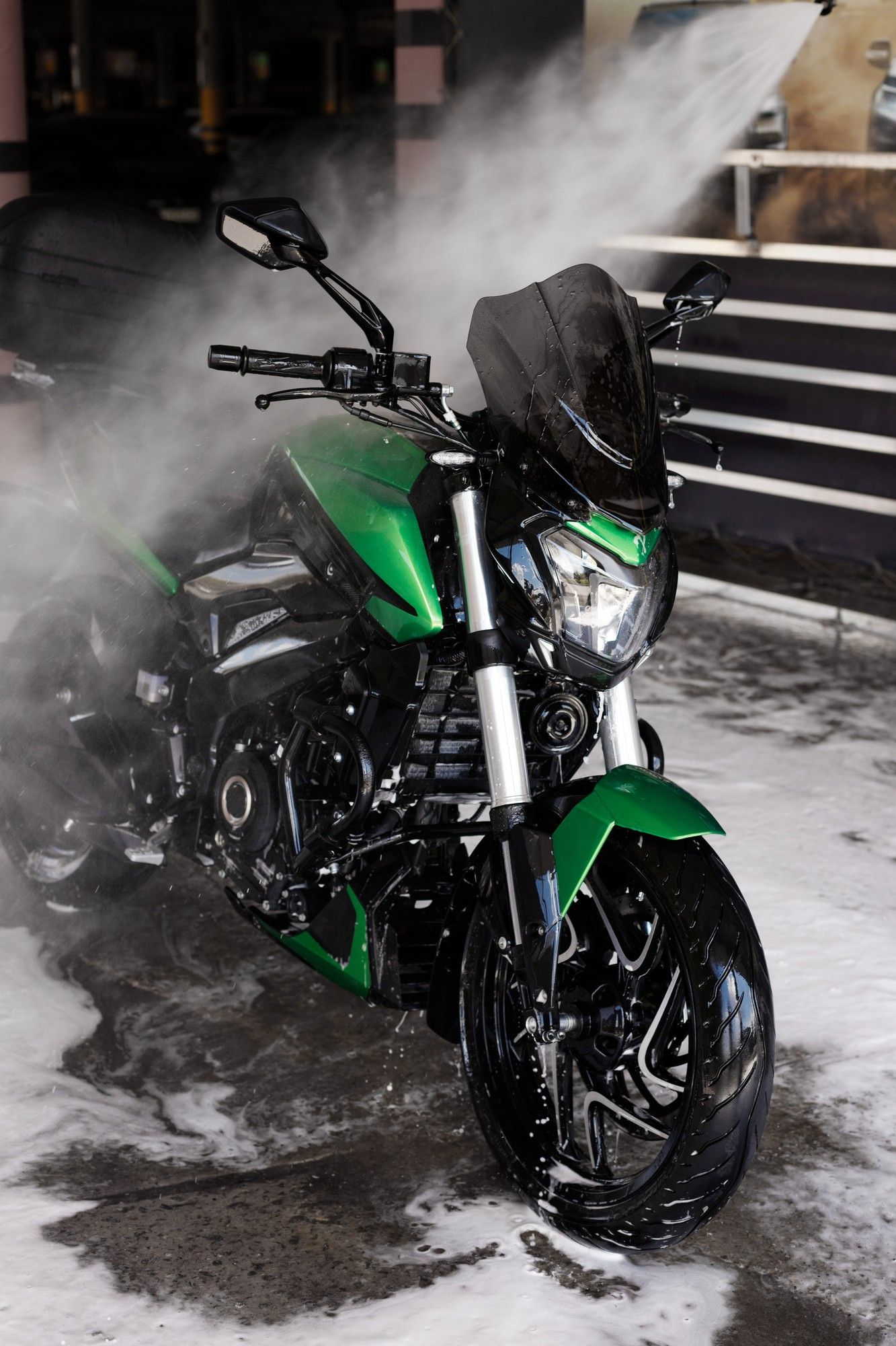 A green and black motorcycle is being washed with foam