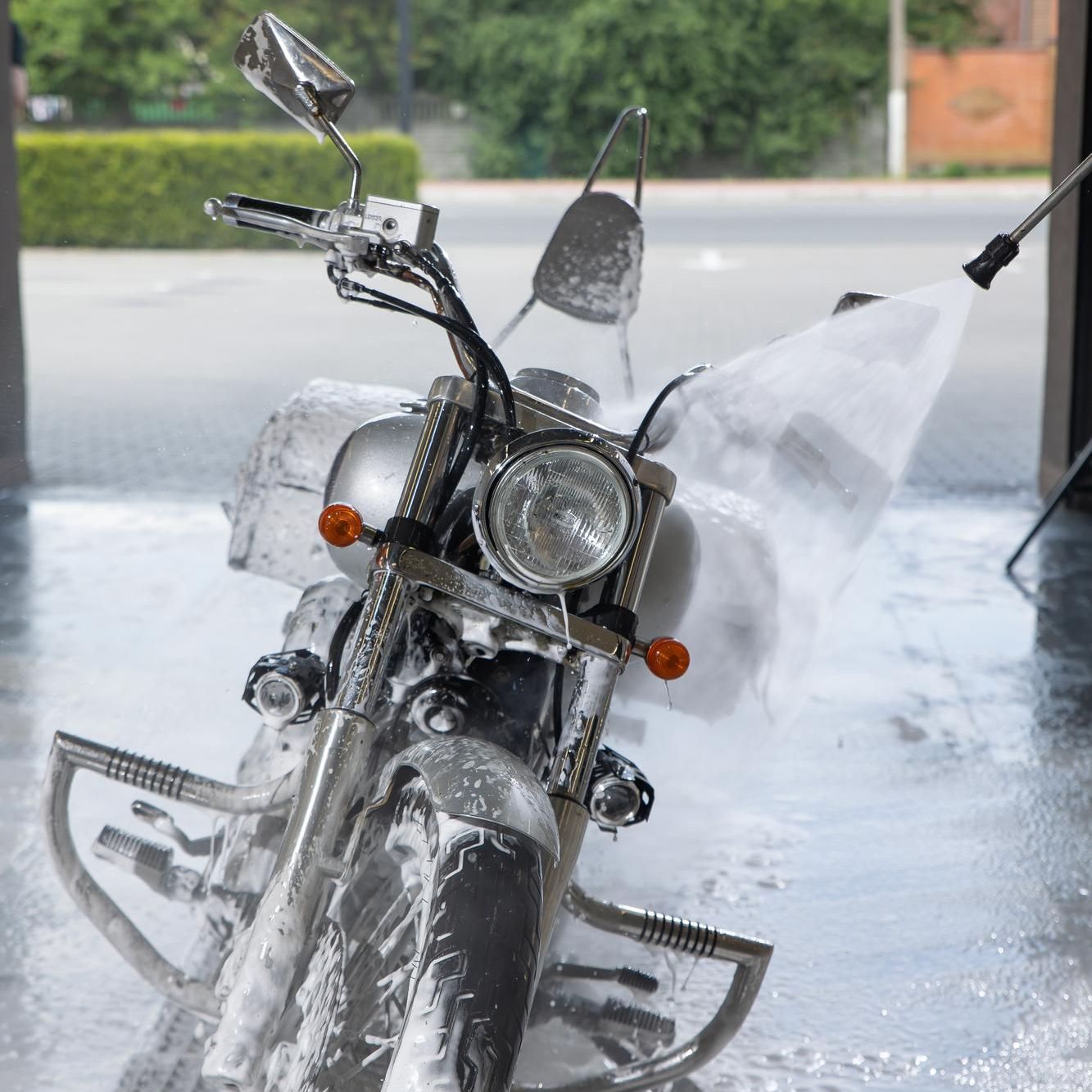 A motorcycle is being cleaned with a high pressure washer
