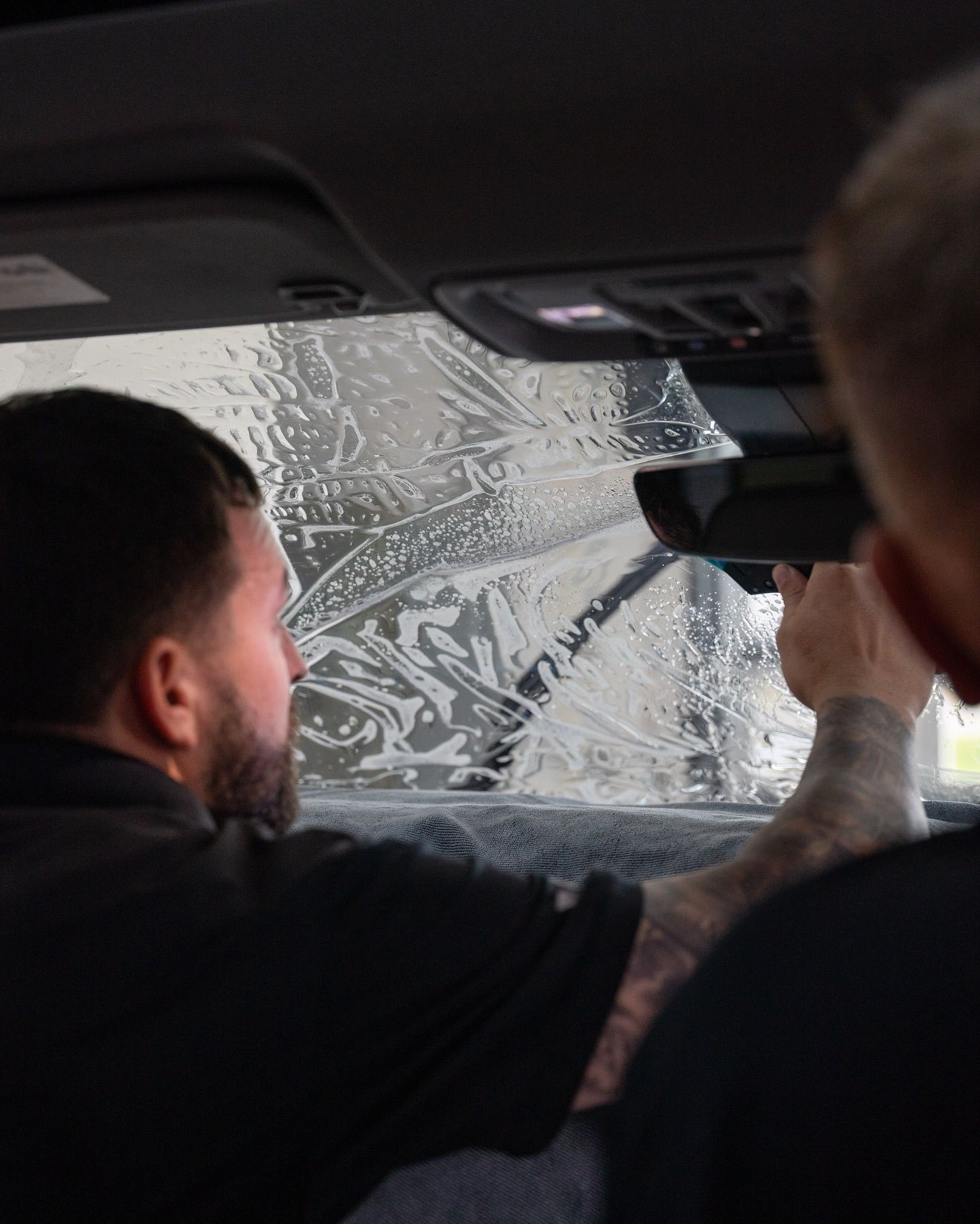 A person is applying window tinting to a car window.