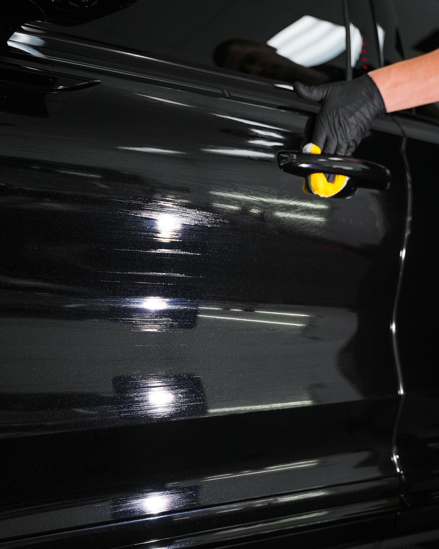 A man is polishing the windshield of a car.