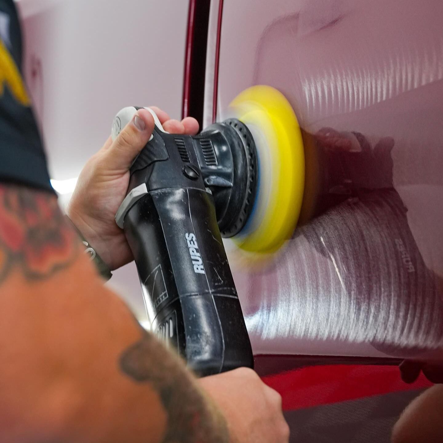 A person is polishing a car with a machine.