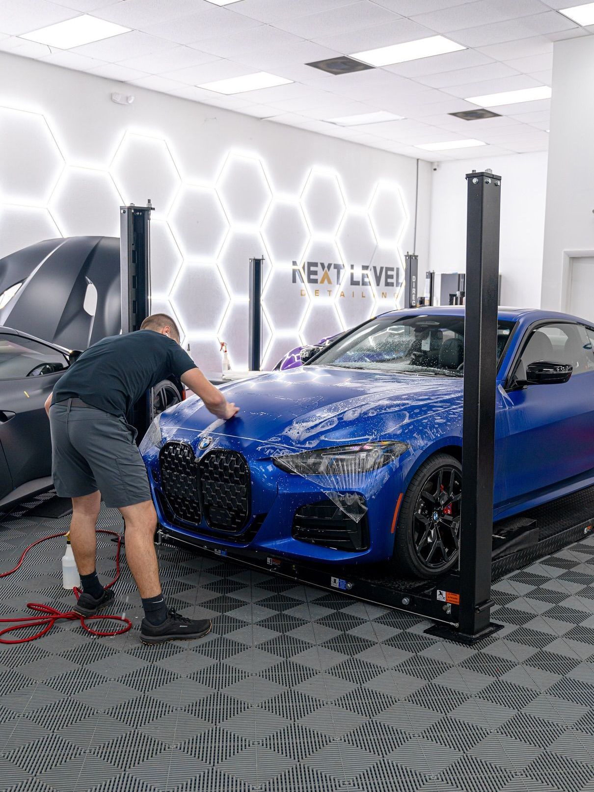 A man is cleaning a white sports car in a garage.