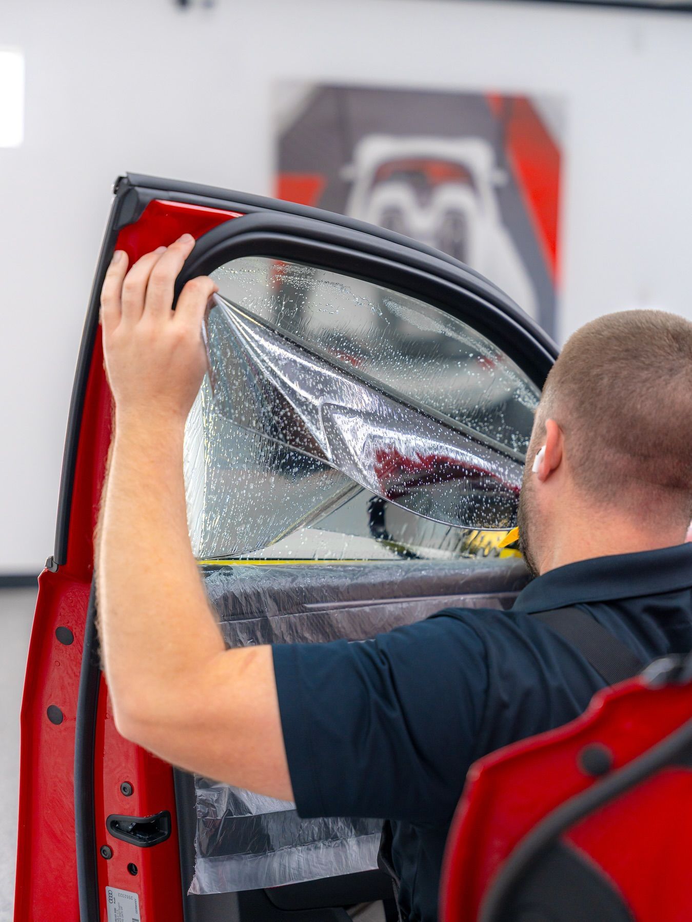 A woman wearing a headlamp is working on a car.