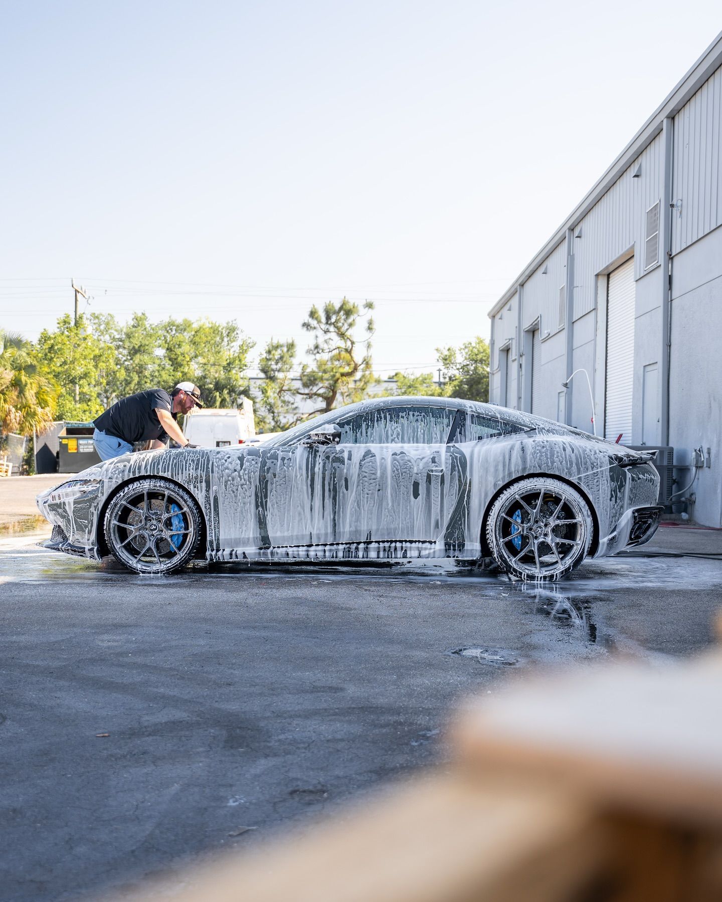 A man is kneeling down to wash a motorcycle.
