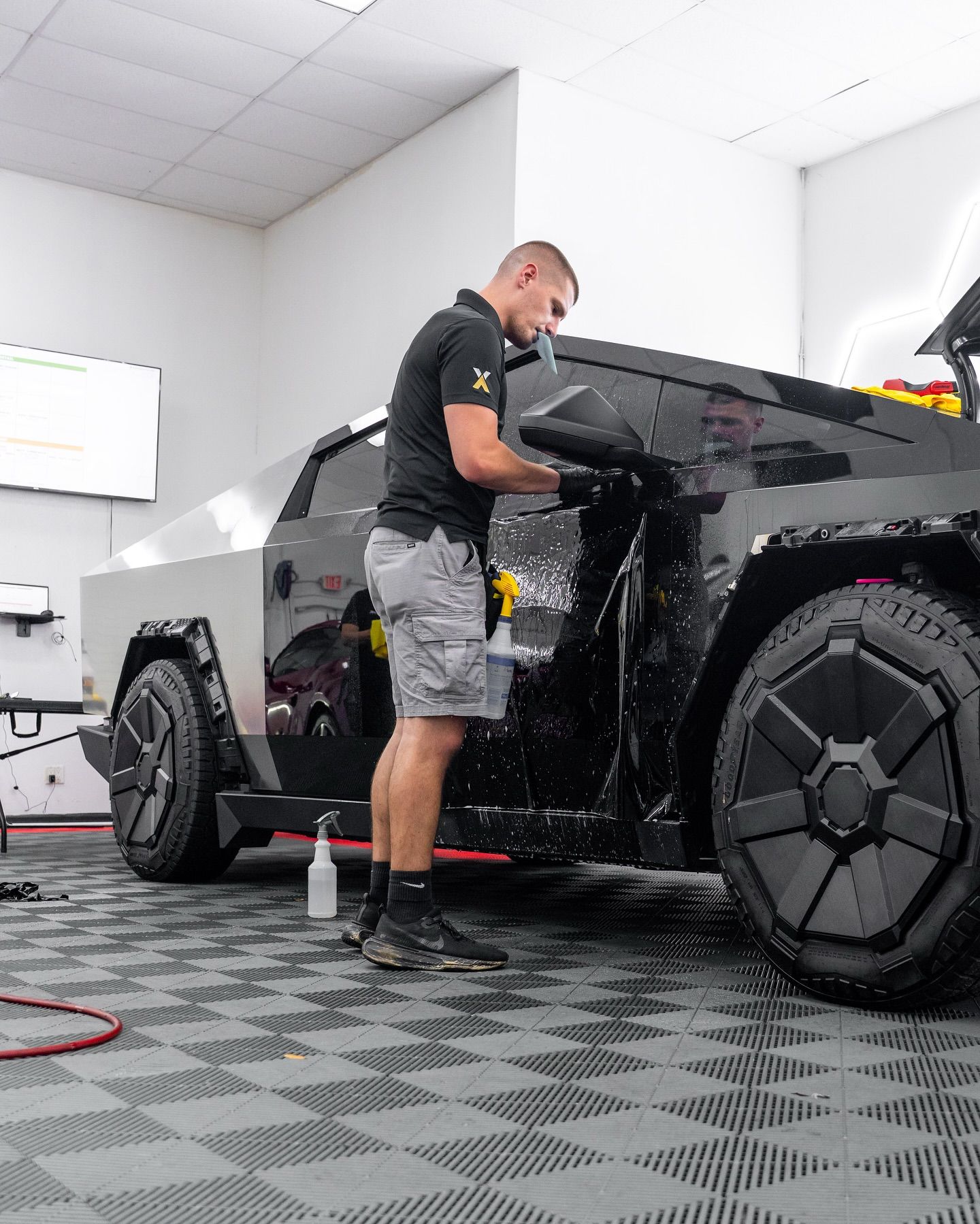 A green tesla model x is parked in a garage with its doors open.