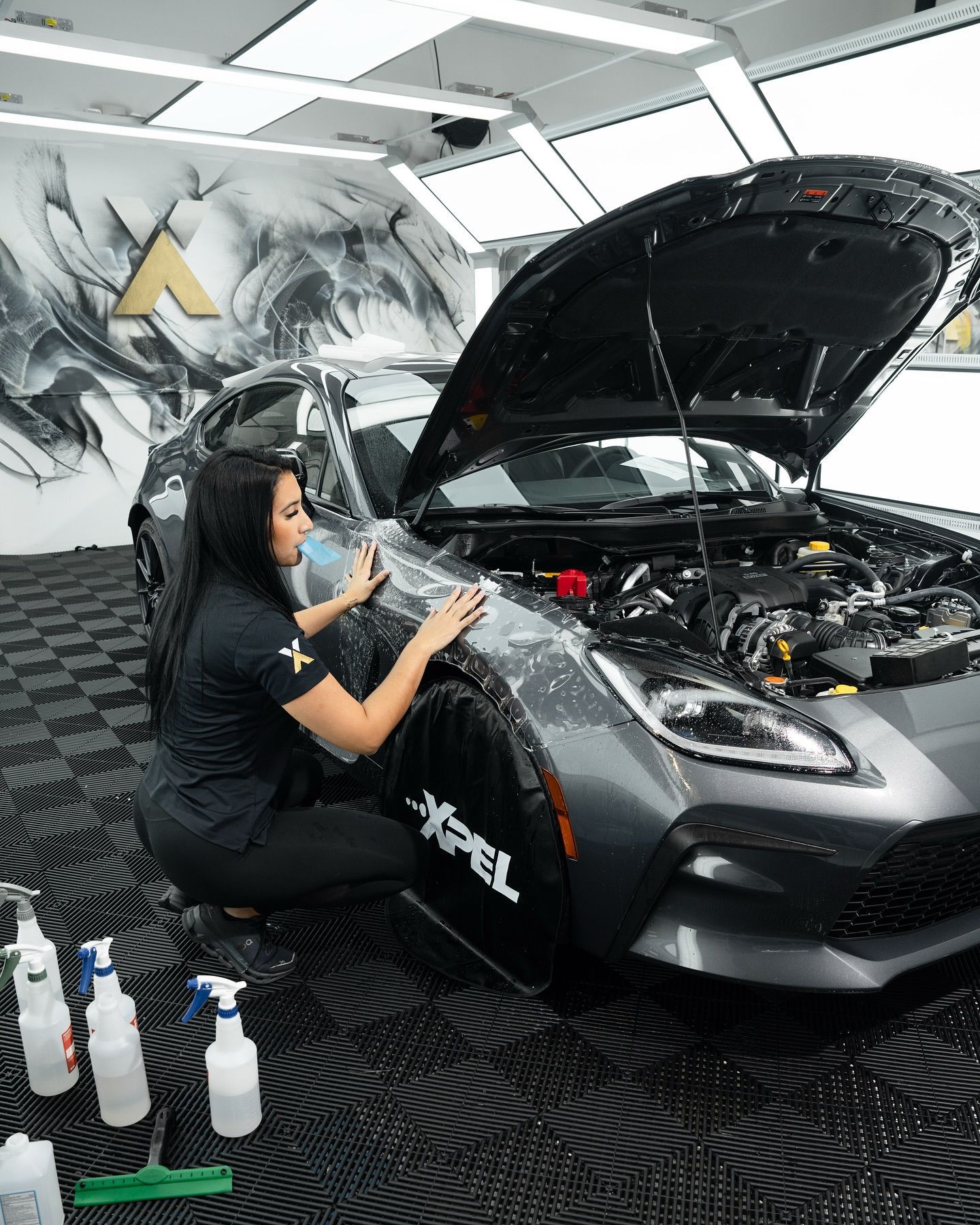 A person is cutting a piece of plastic on a car with scissors.
