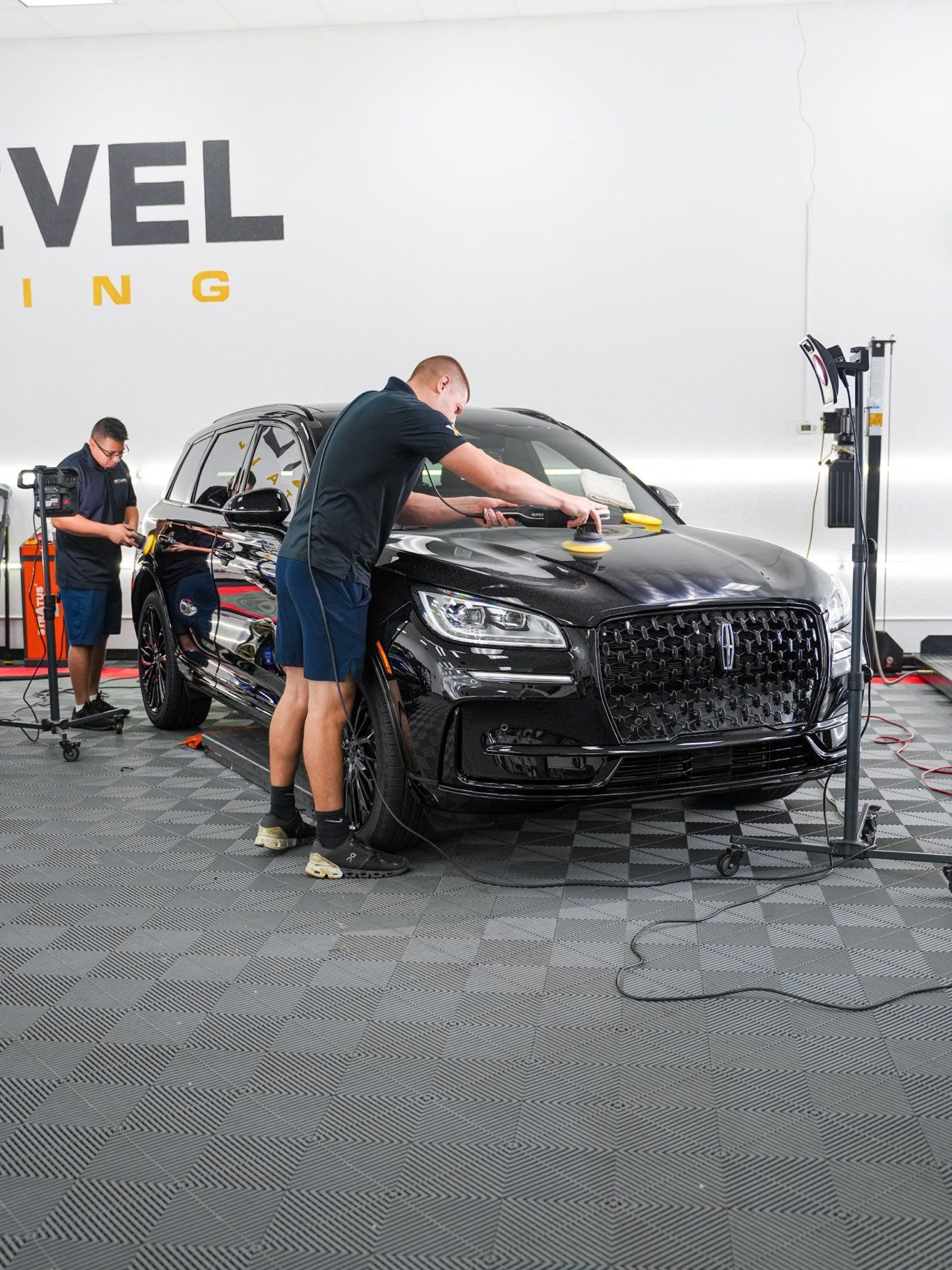 A person is polishing a red car with a machine.