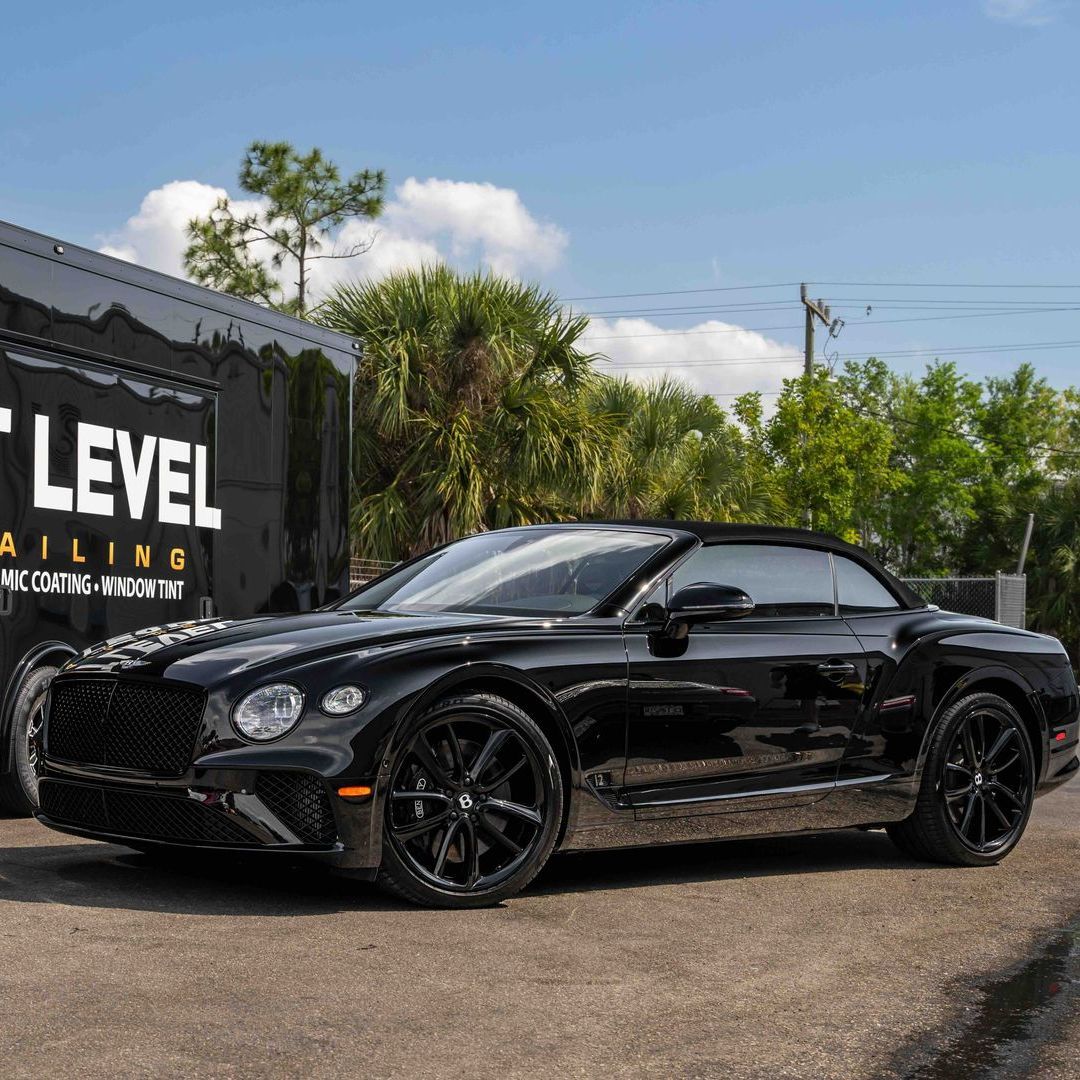A black bentley convertible is parked in front of a building.