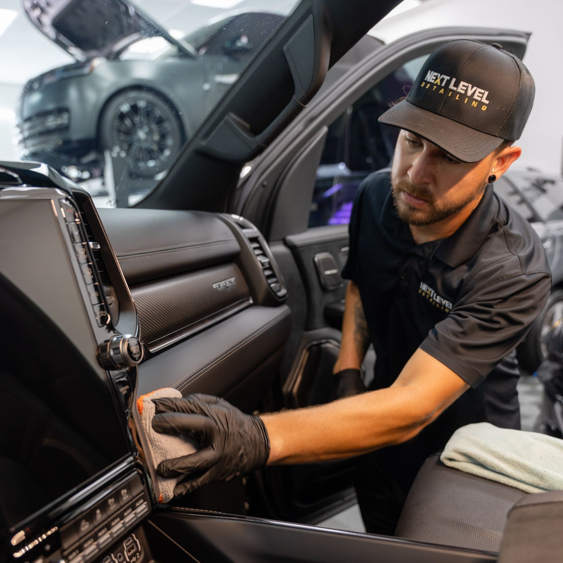 A man wearing a hat that says next level is cleaning the interior of a car