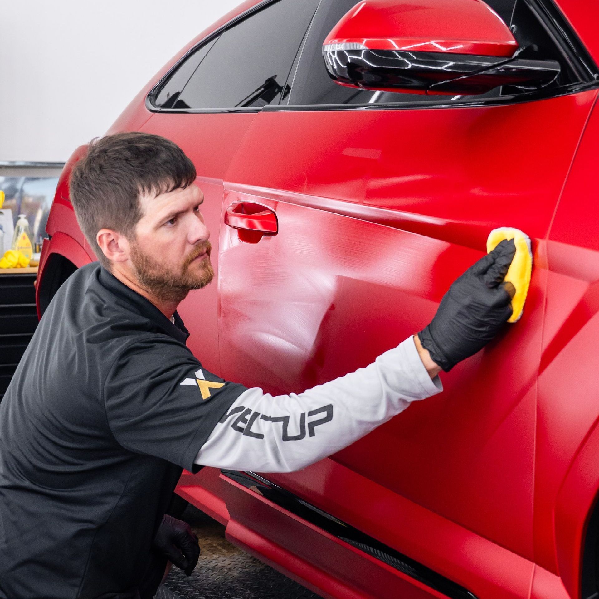A person is cleaning a car with a cloth