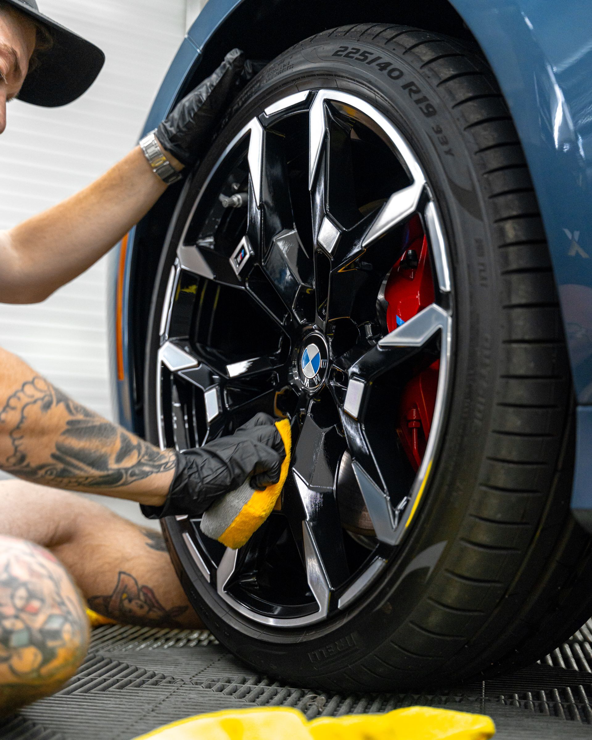 A man is cleaning the wheel of a car with a sponge.