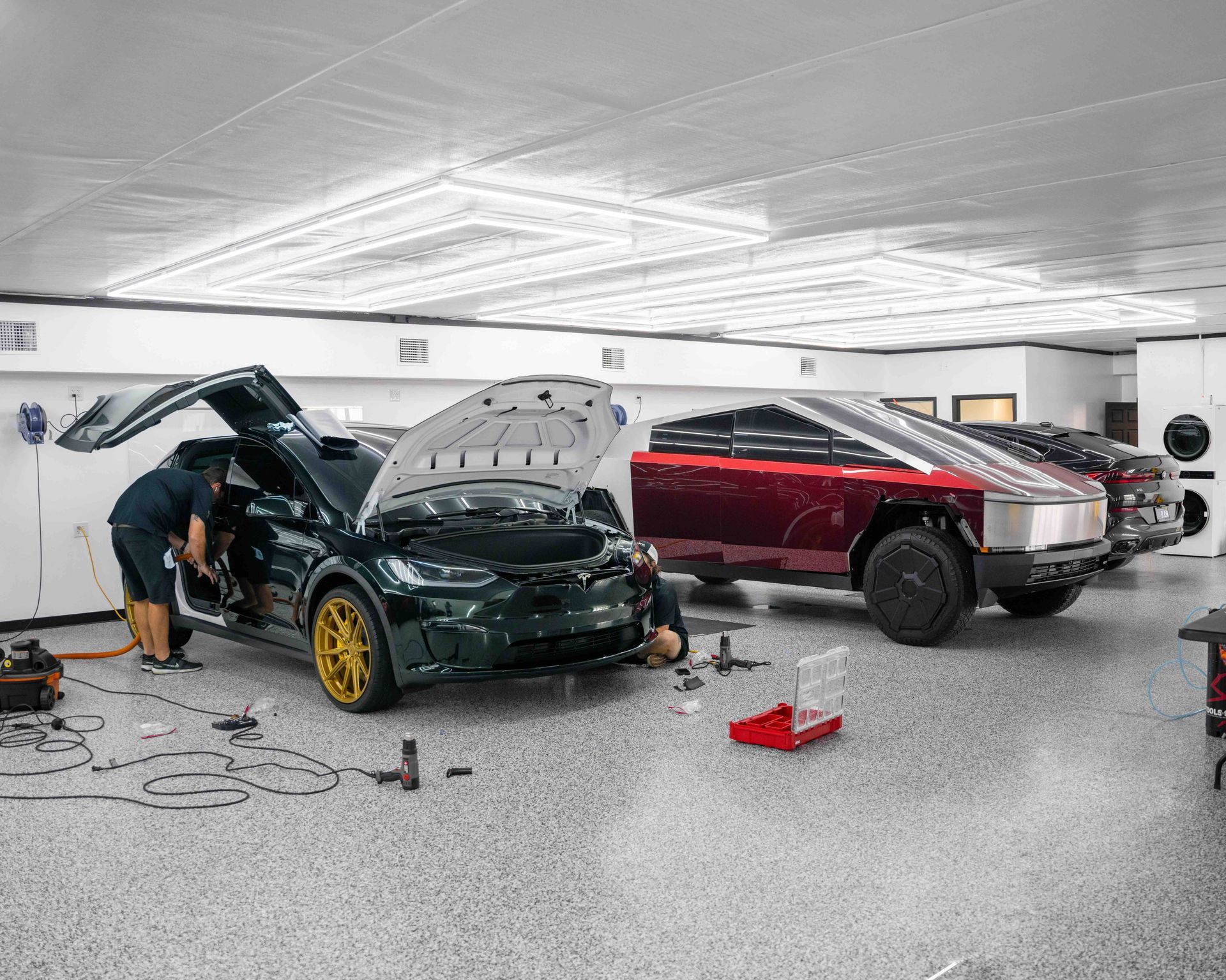 A man is working on a tesla model x in a garage.