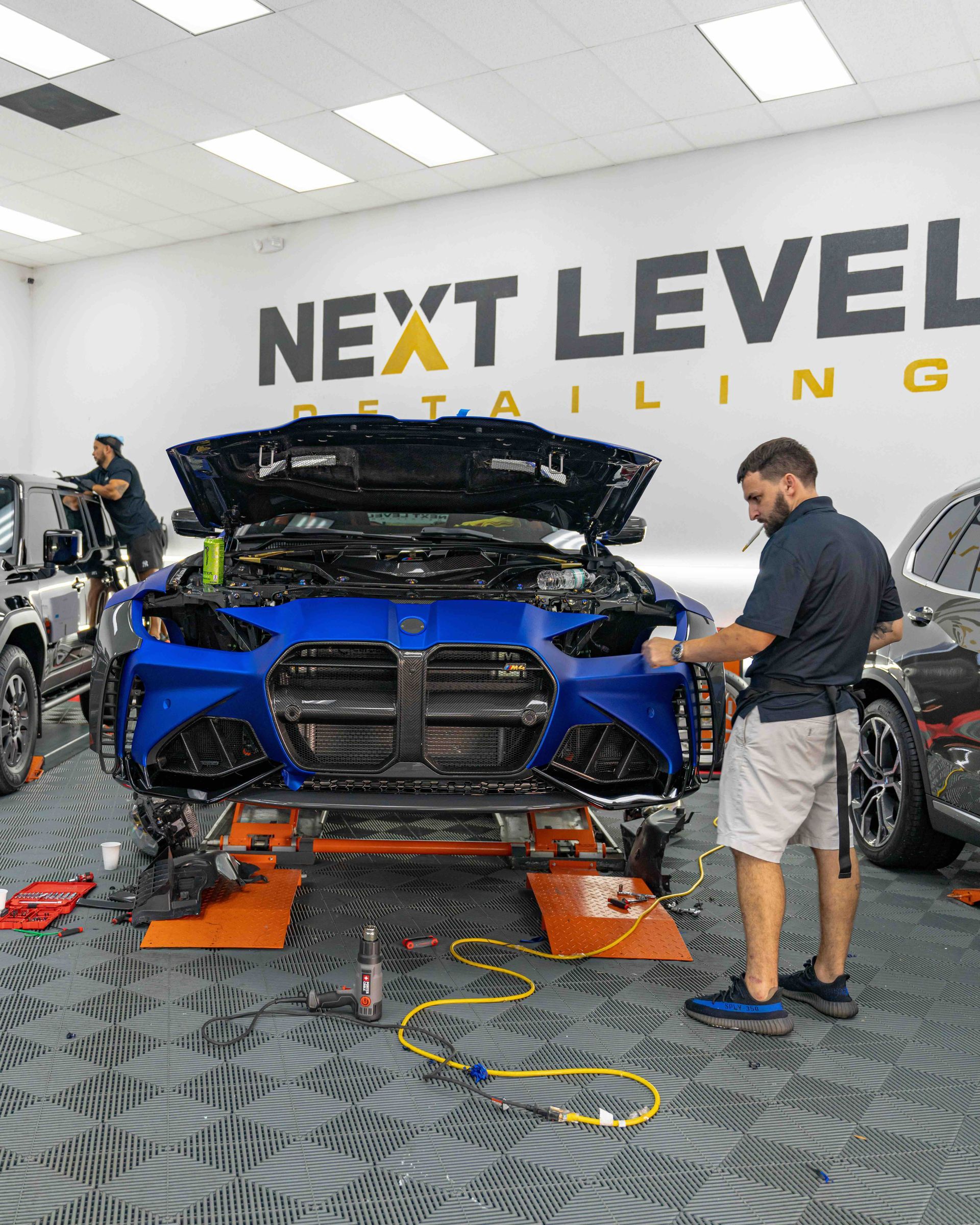 A man is working on a blue car in a garage.