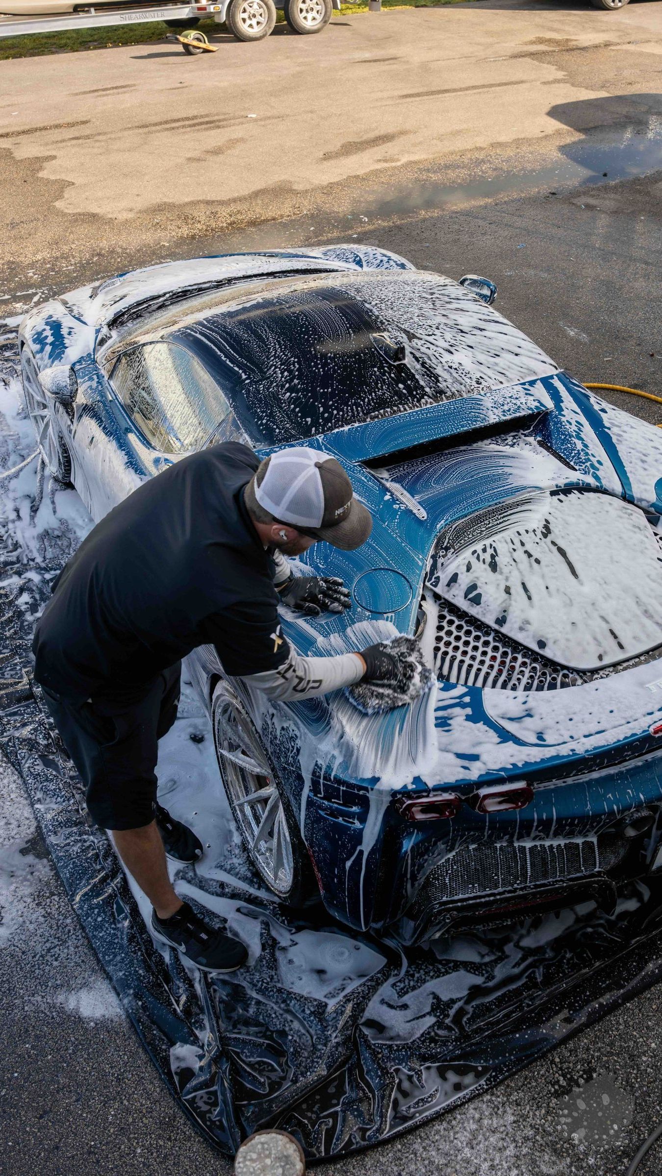 A man is washing a blue sports car with foam.