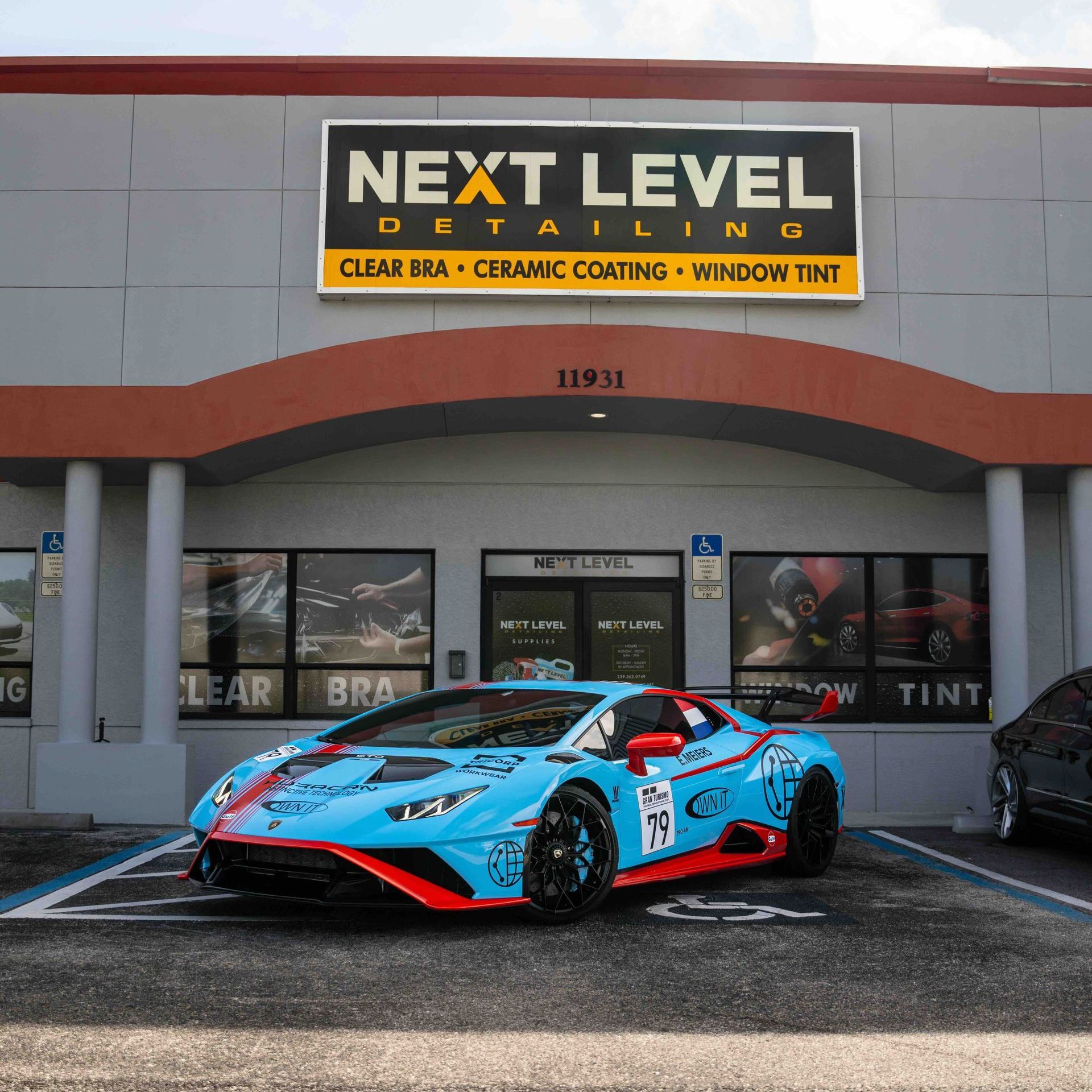 A blue sports car is parked in front of a next level detailing shop