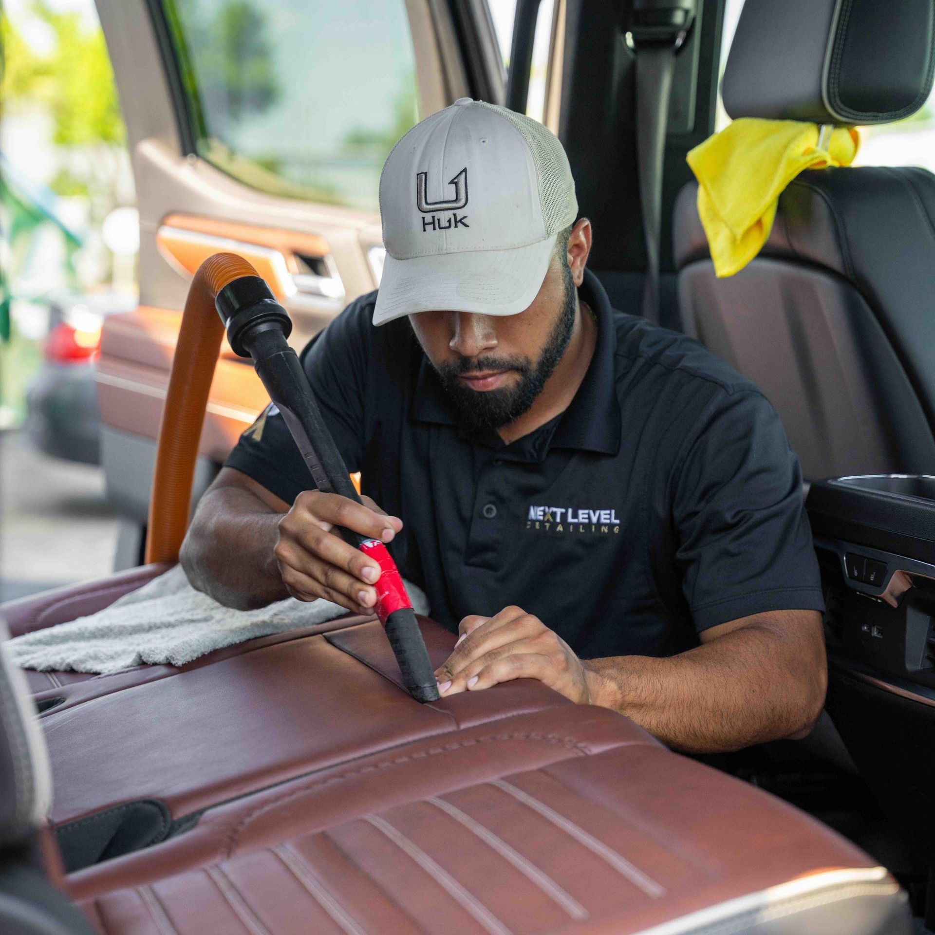 A man is cleaning the interior of a car with a vacuum cleaner.