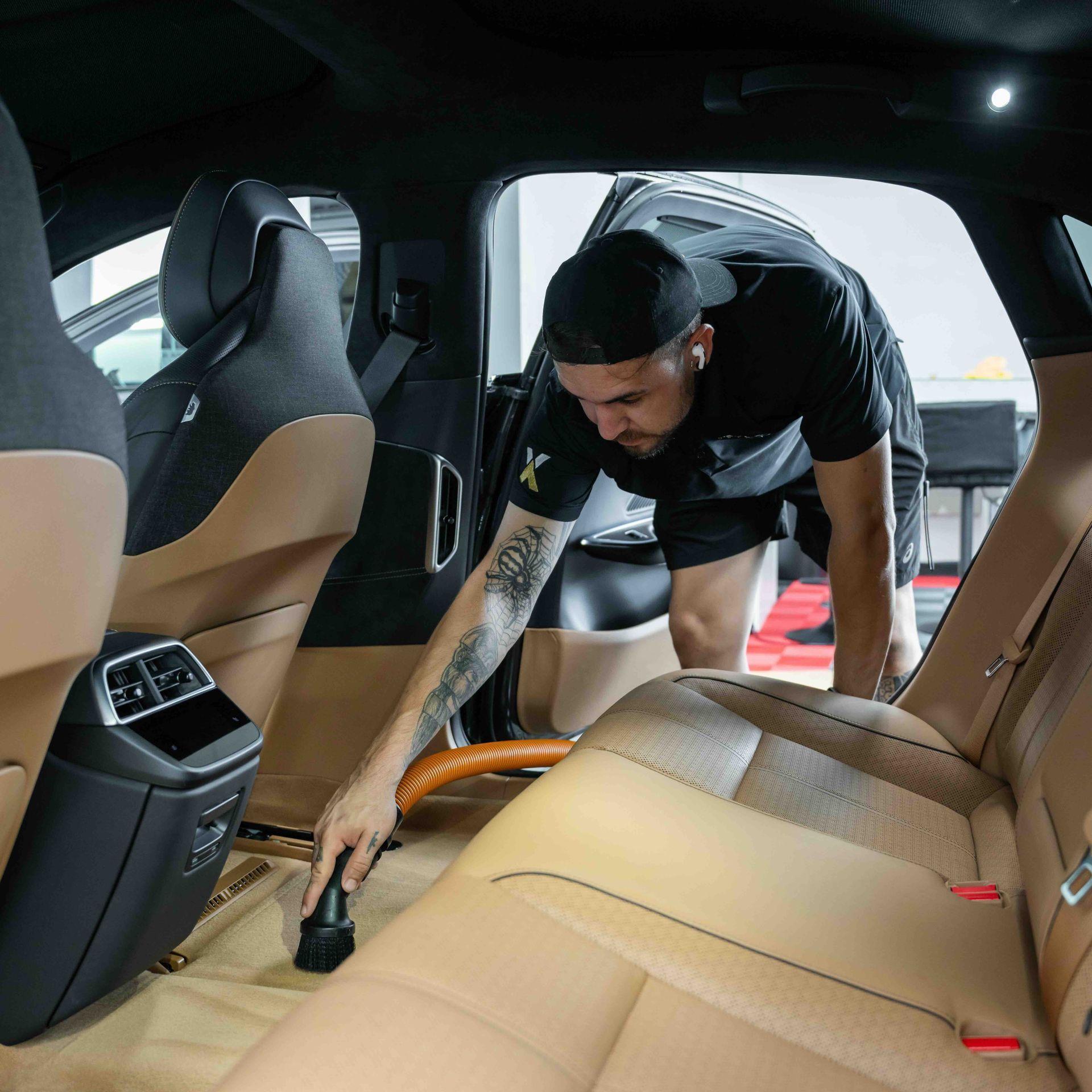 A man is cleaning the interior of a car with a vacuum cleaner