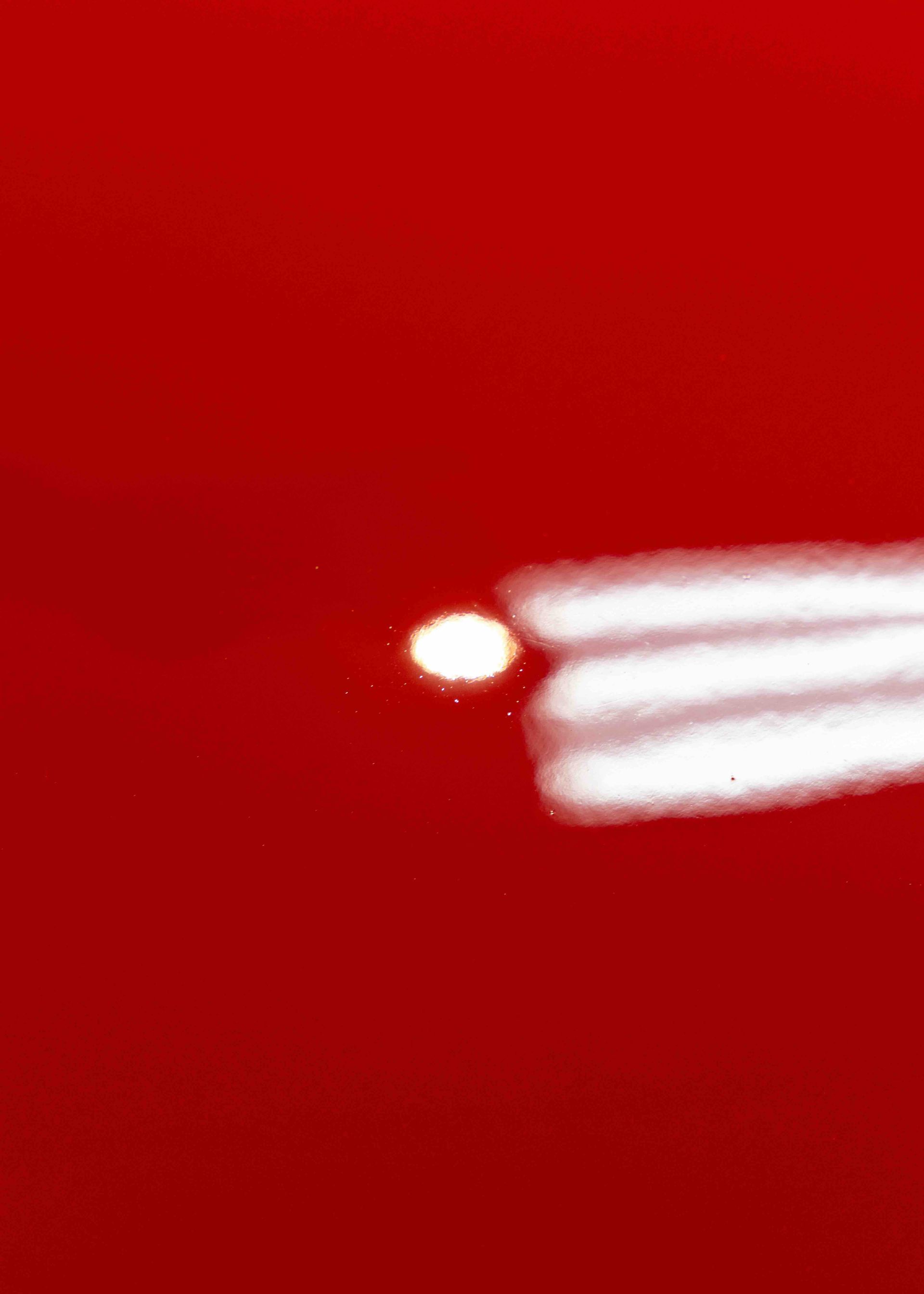 A close up of a red car with a white spot on it.