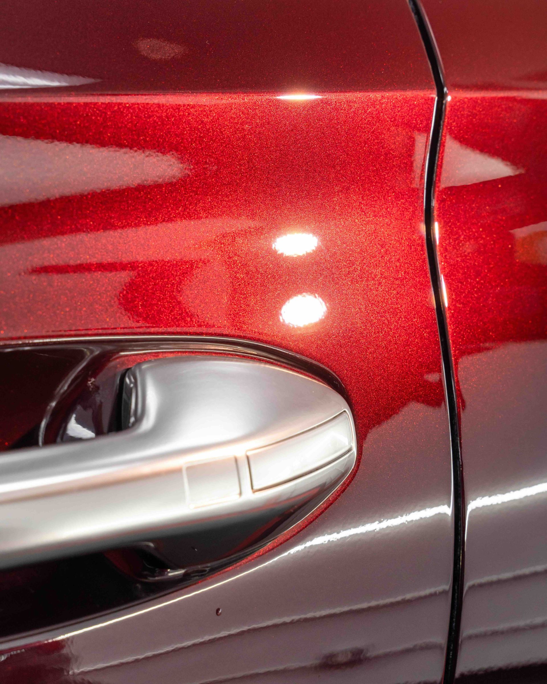 A close up of the door handle of a red car