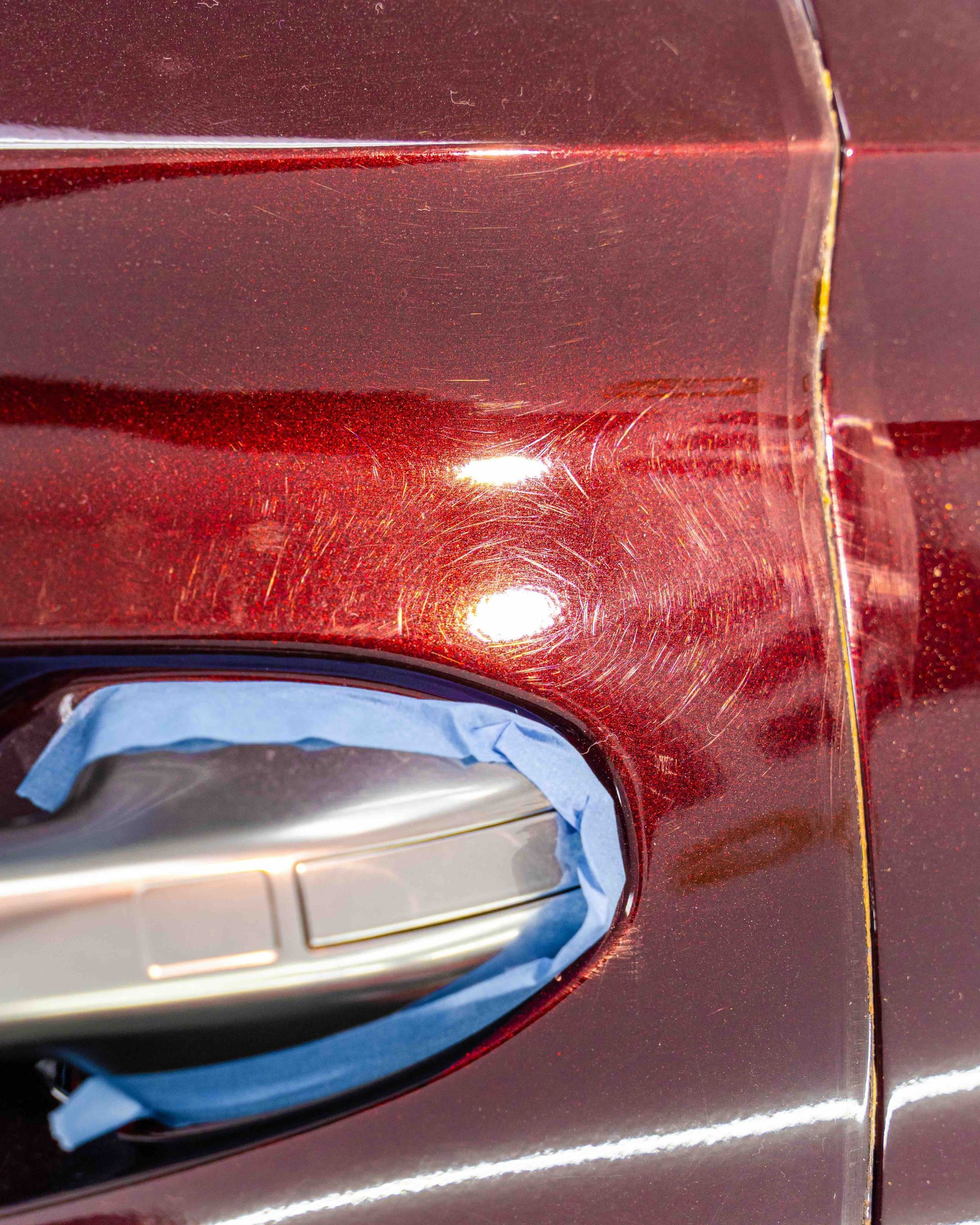 A close up of a car door handle with blue tape on it