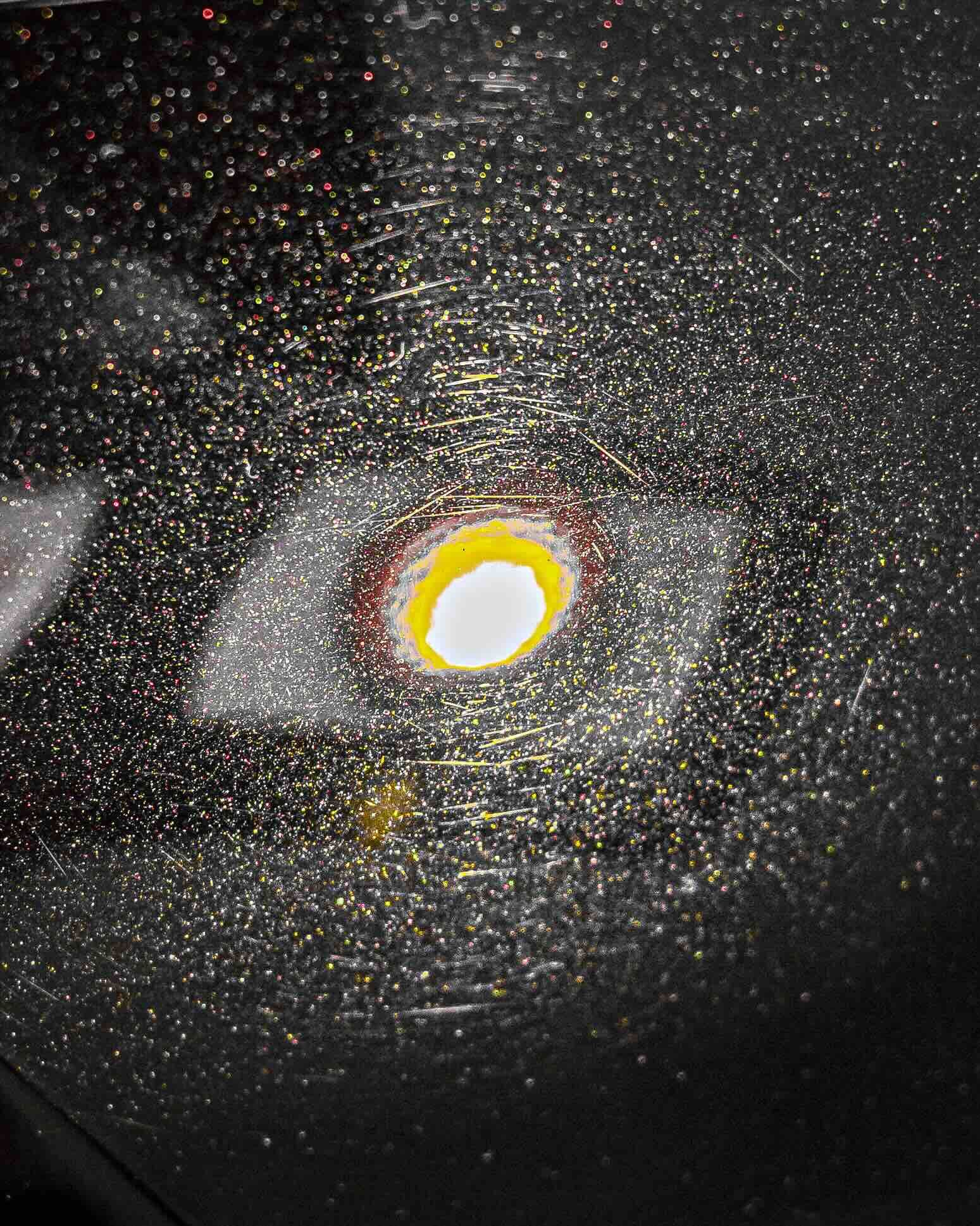 A close up of a black surface with a yellow circle in the middle.