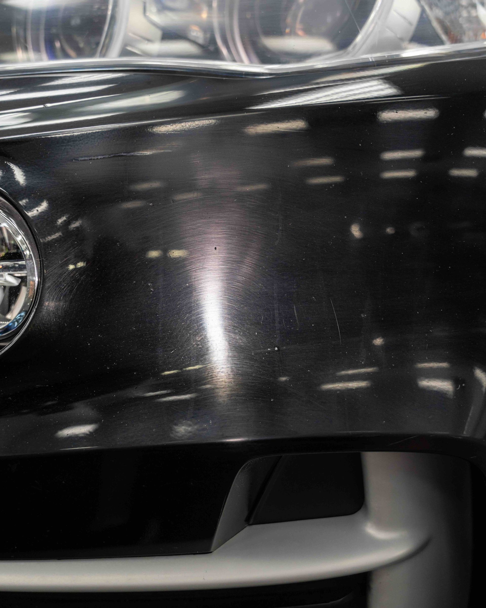 A close up of the front of a black car with a nissan logo on it.