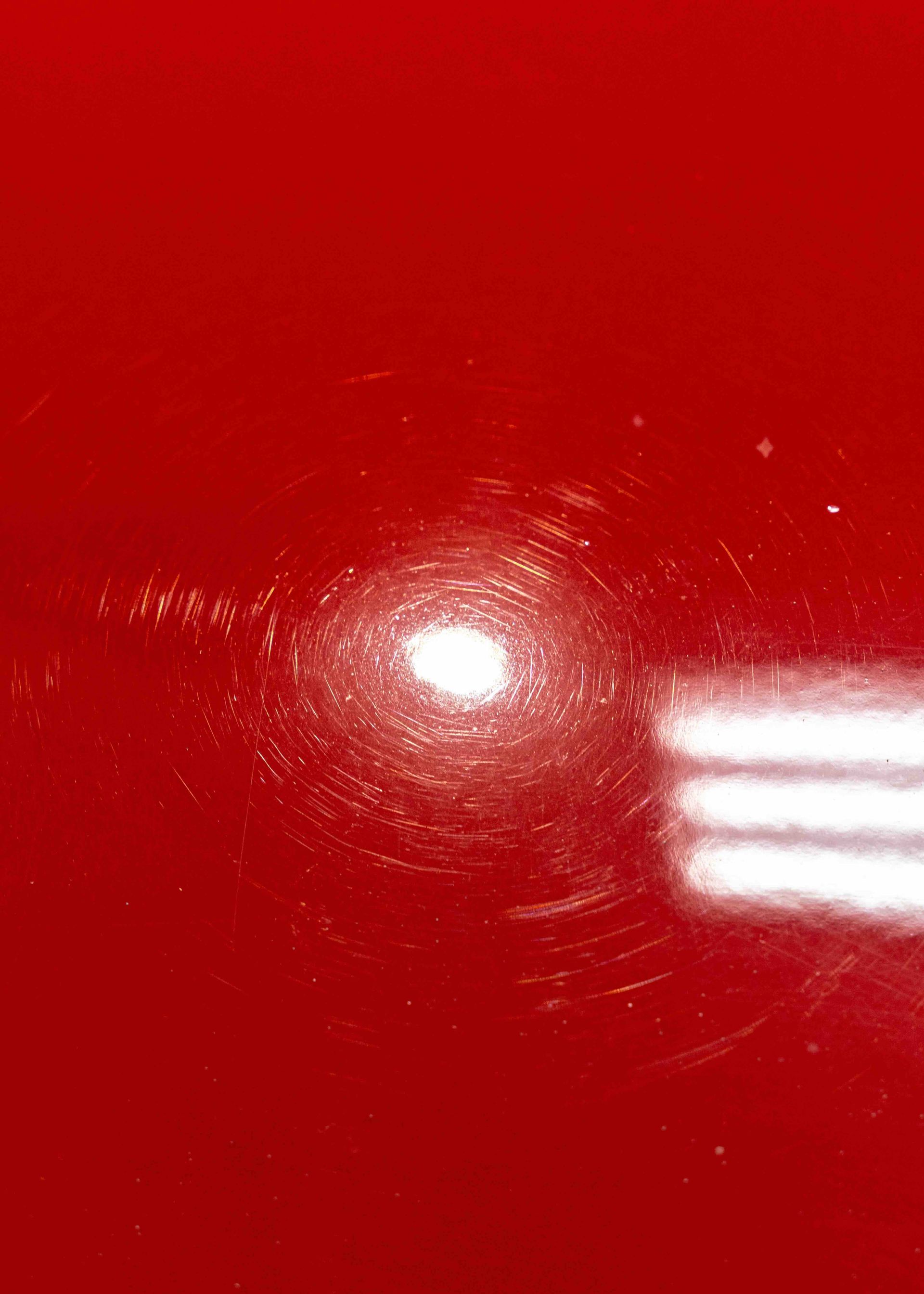 A close up of a red car with a white light shining on it.