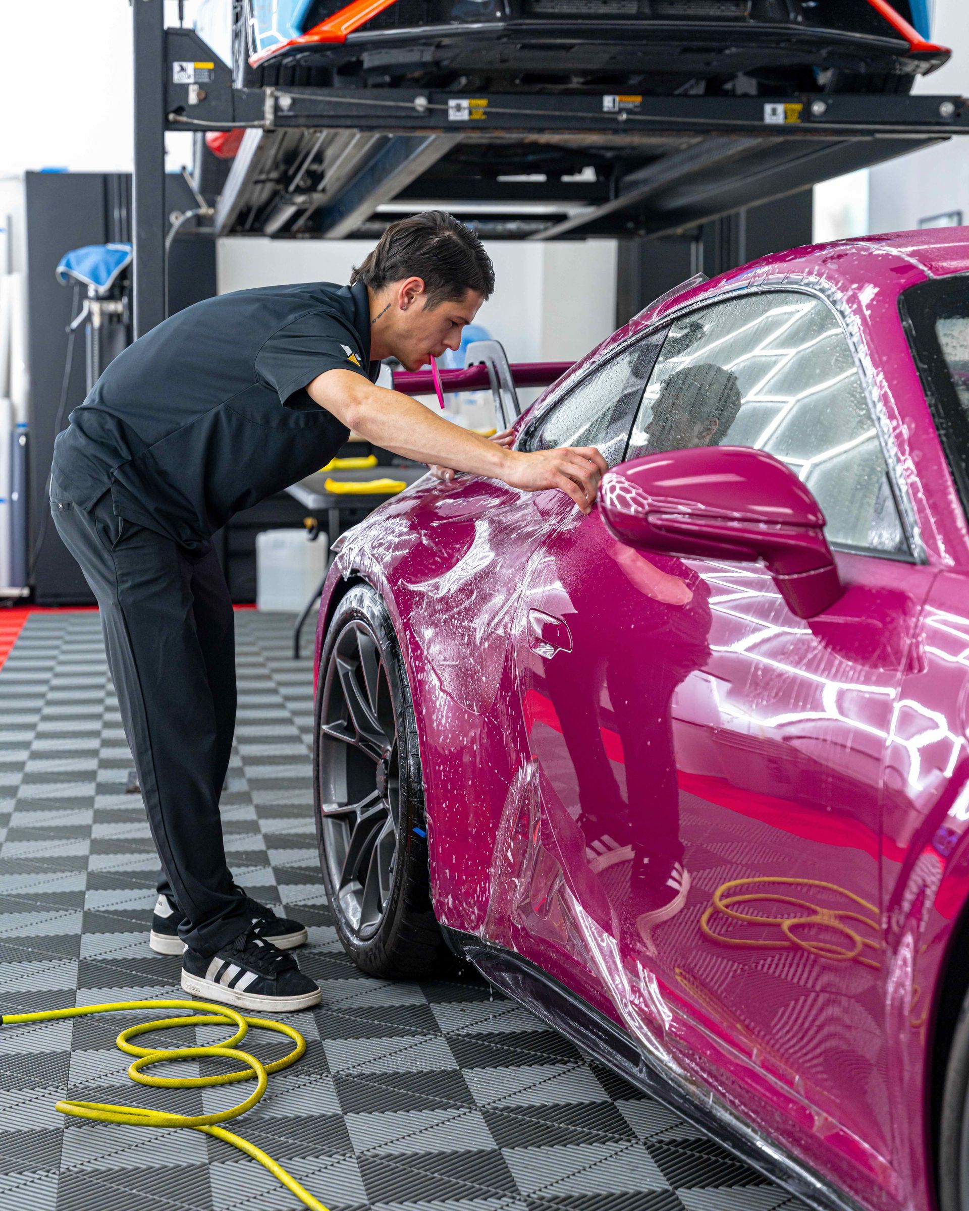 A man is washing a purple sports car in a garage.
