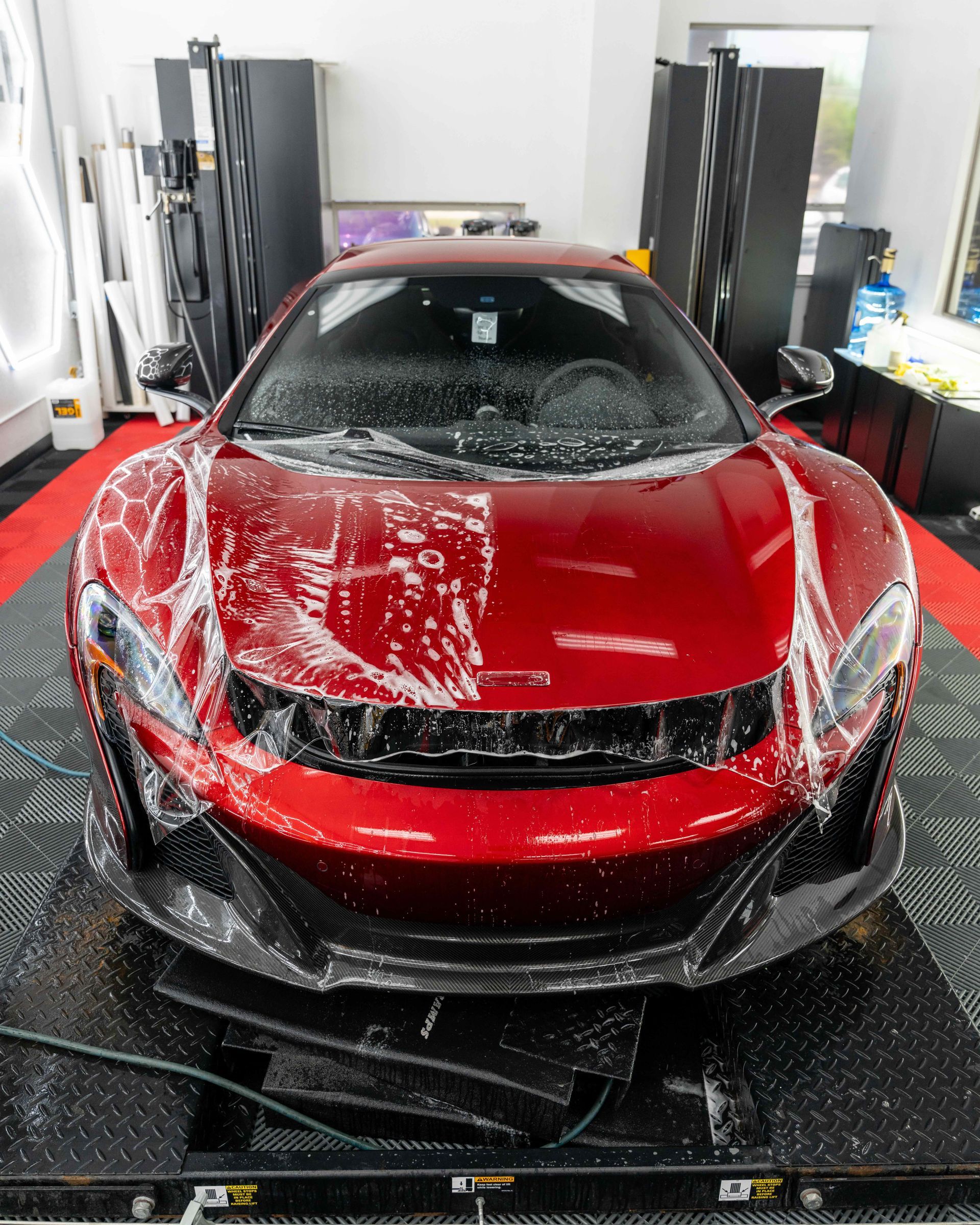 A man is washing a blue sports car in a garage.
