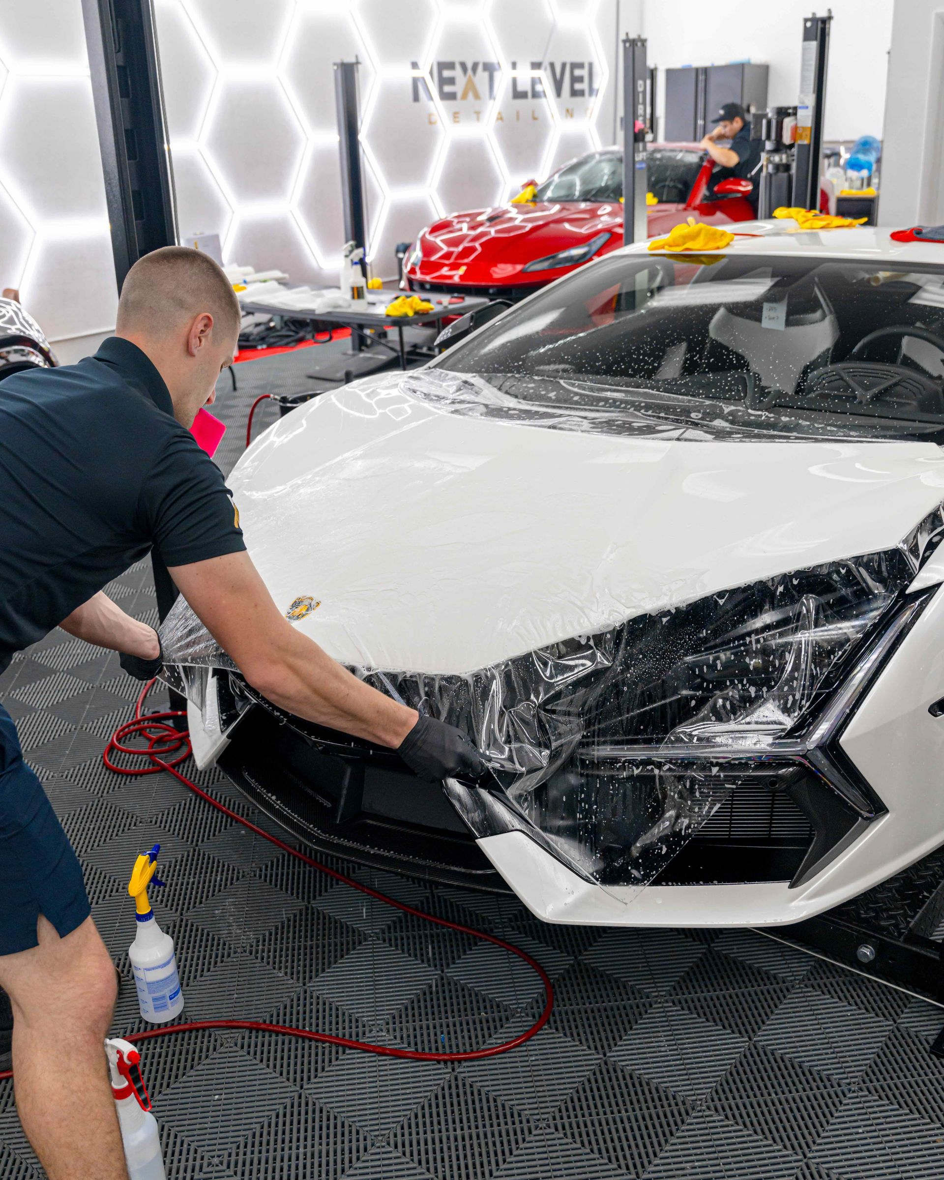 A man is cleaning a white sports car in a garage.