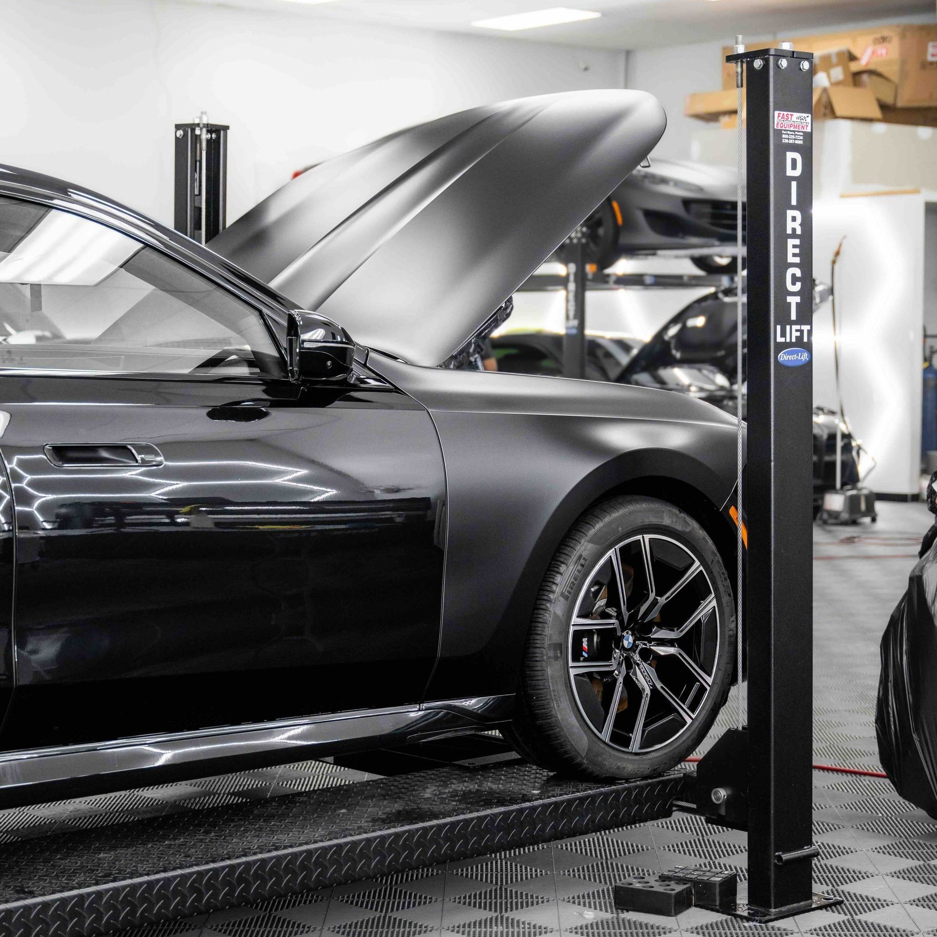 A black car is on a lift with the hood up