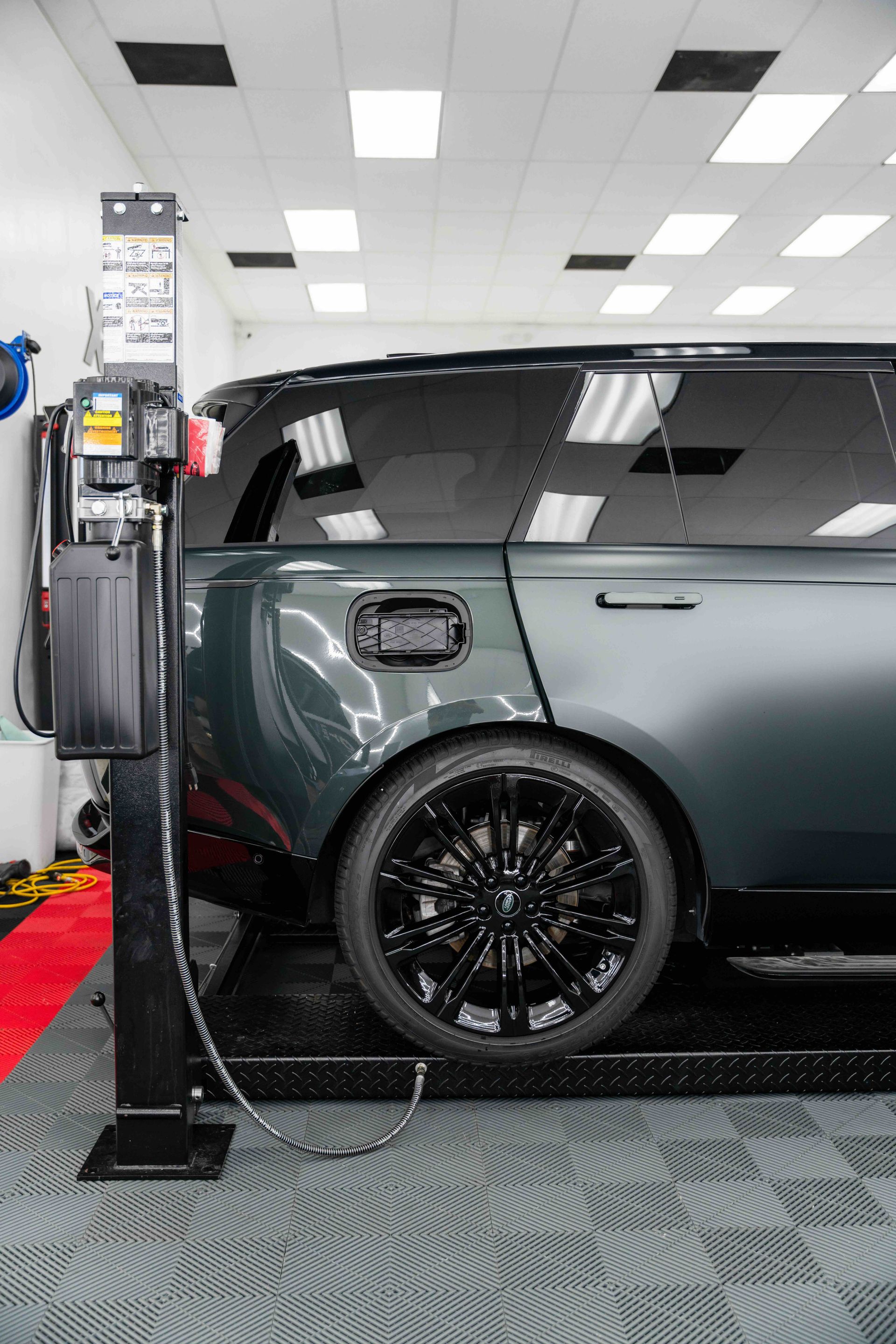 A range rover is sitting on a lift in a garage.