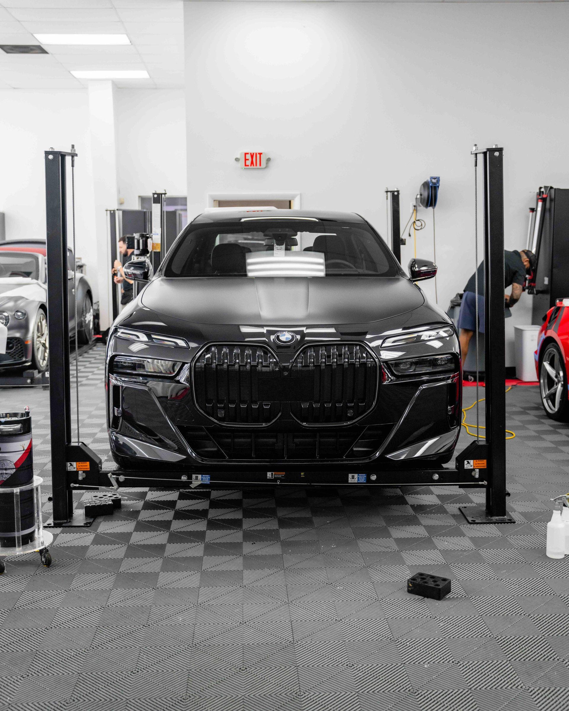 A black car is parked on a lift in a garage.