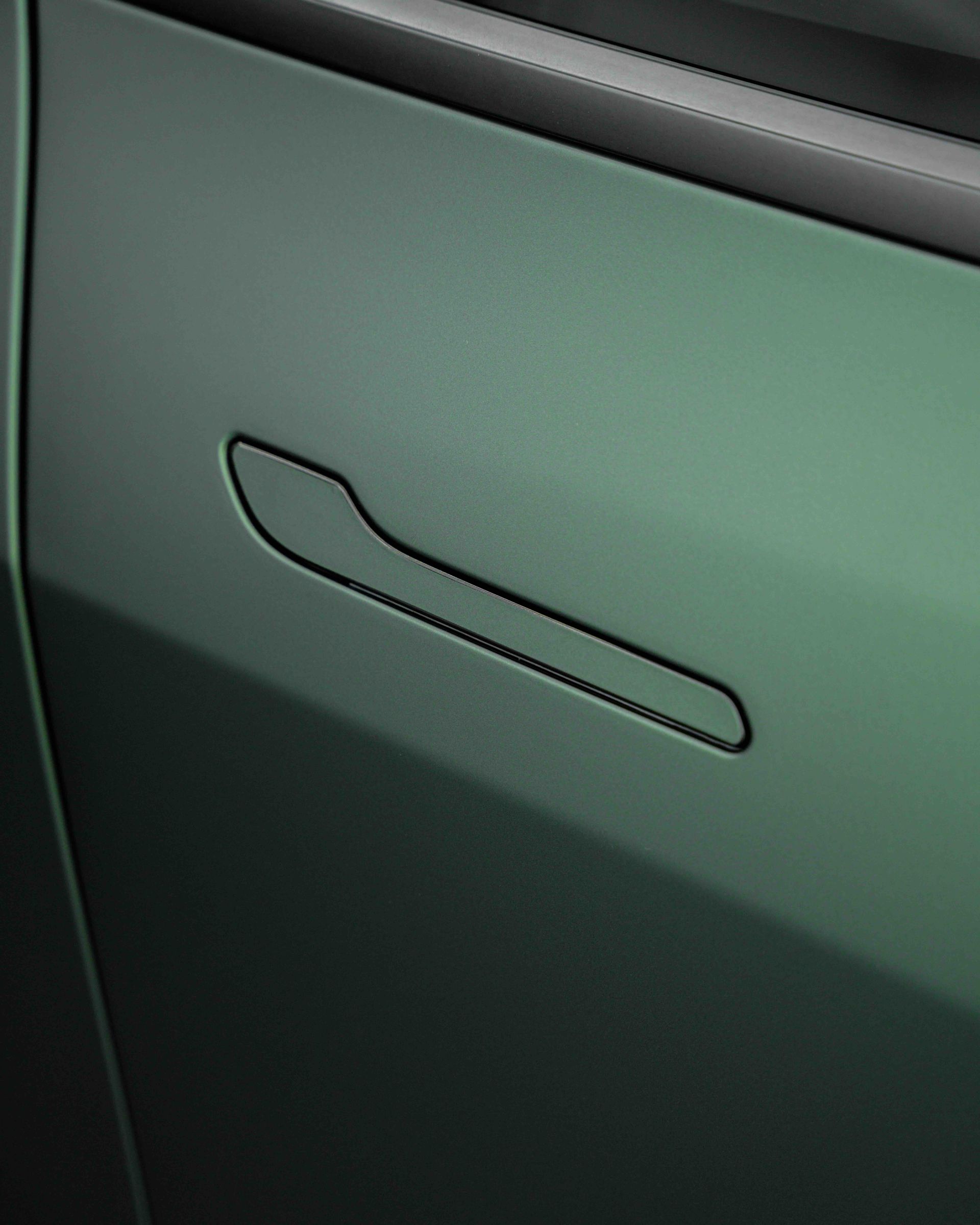 A close up of a green car door handle.