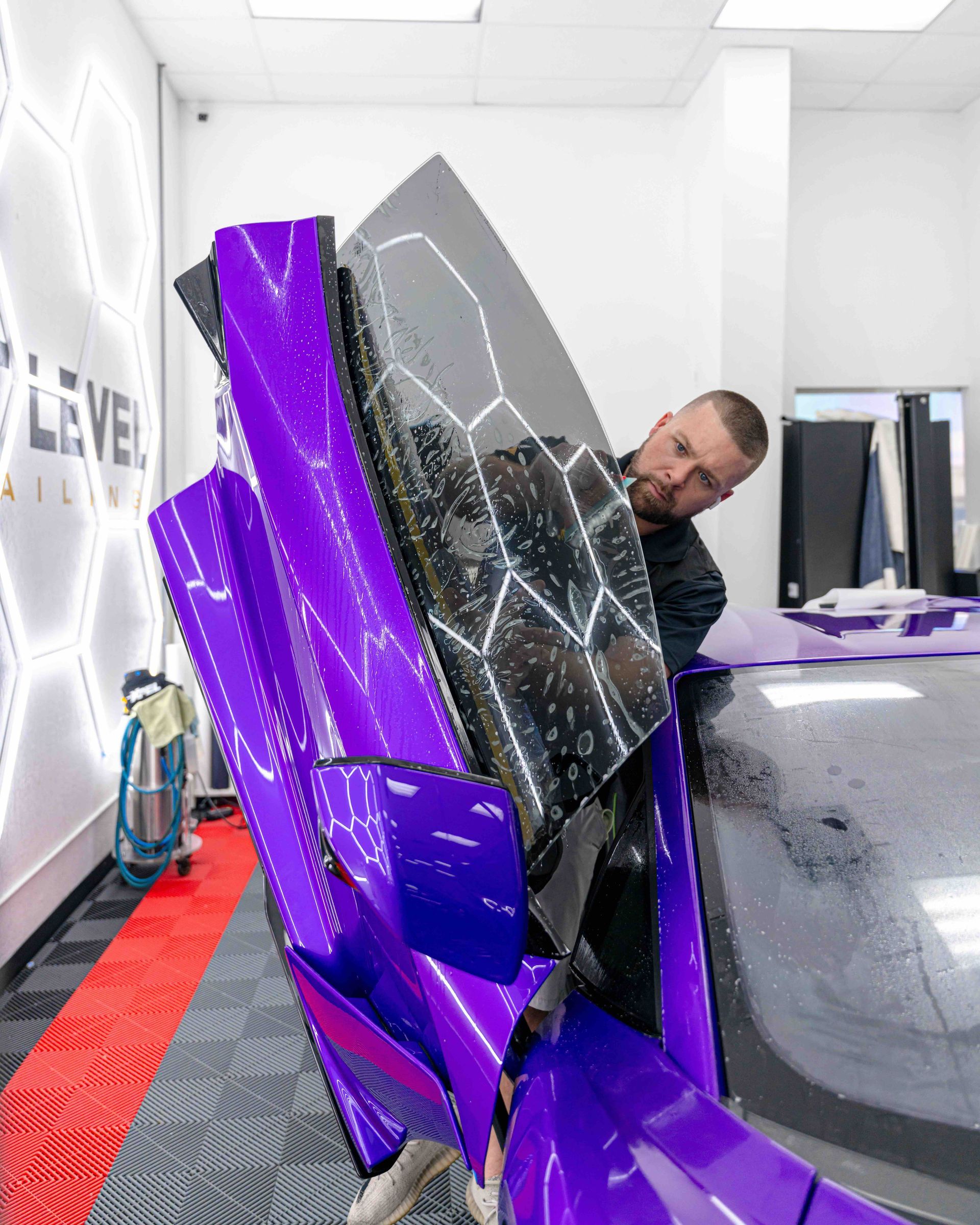 A man is standing next to a purple car in a room.