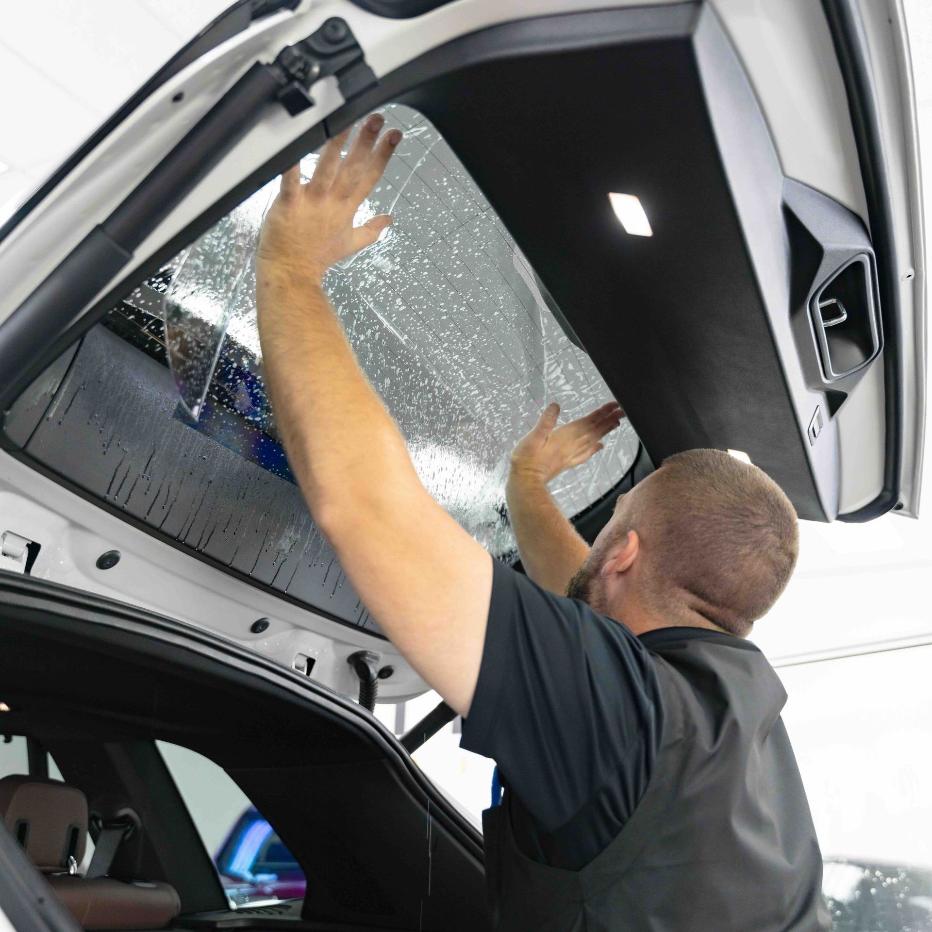A man in a black shirt is opening the trunk of a car