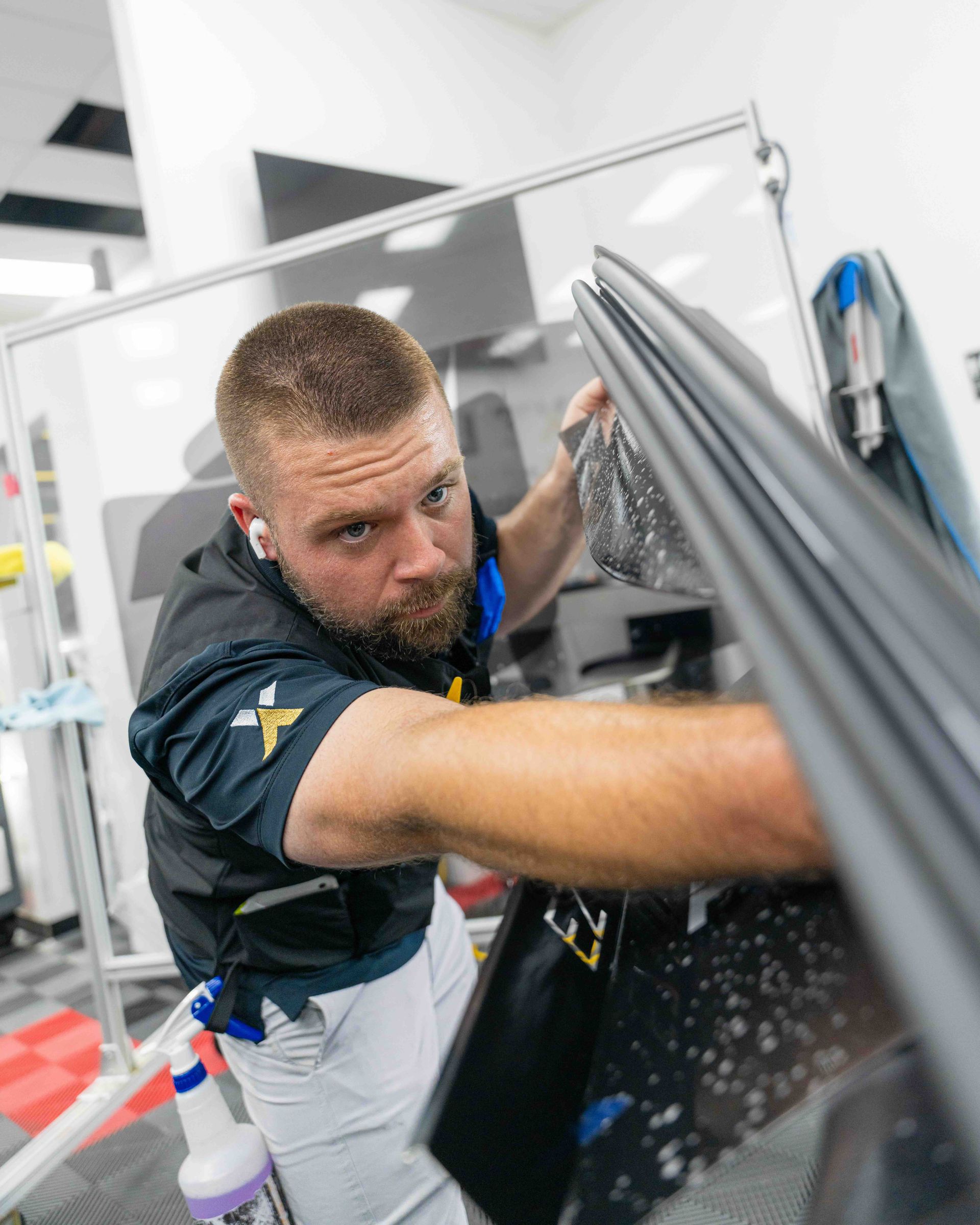 A man is cleaning a car window with a spray bottle.