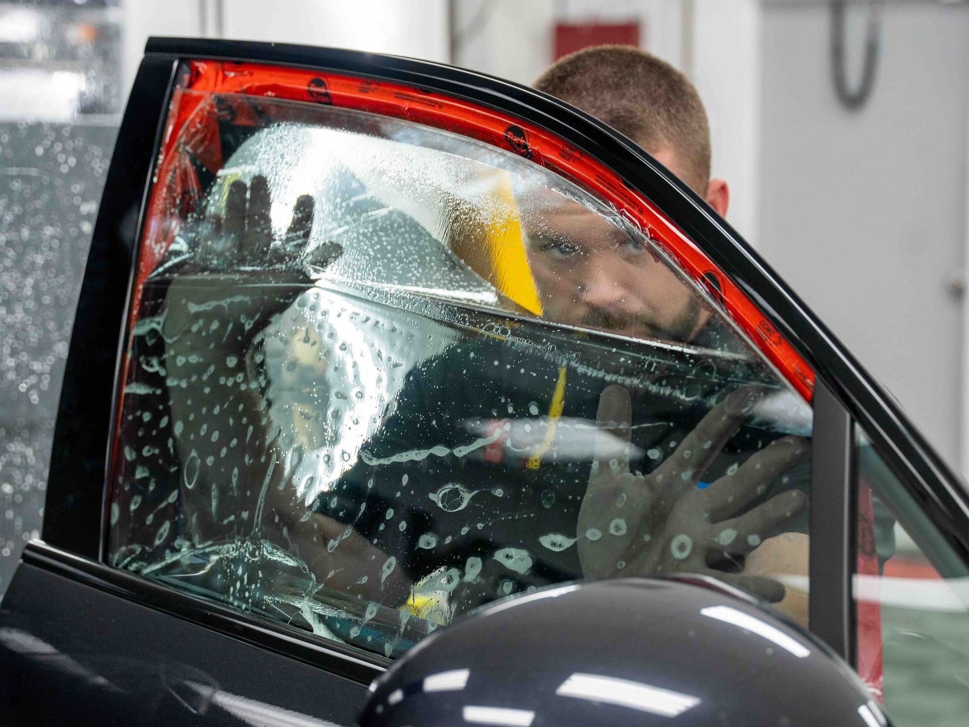 A man is applying window tinting to a car window.