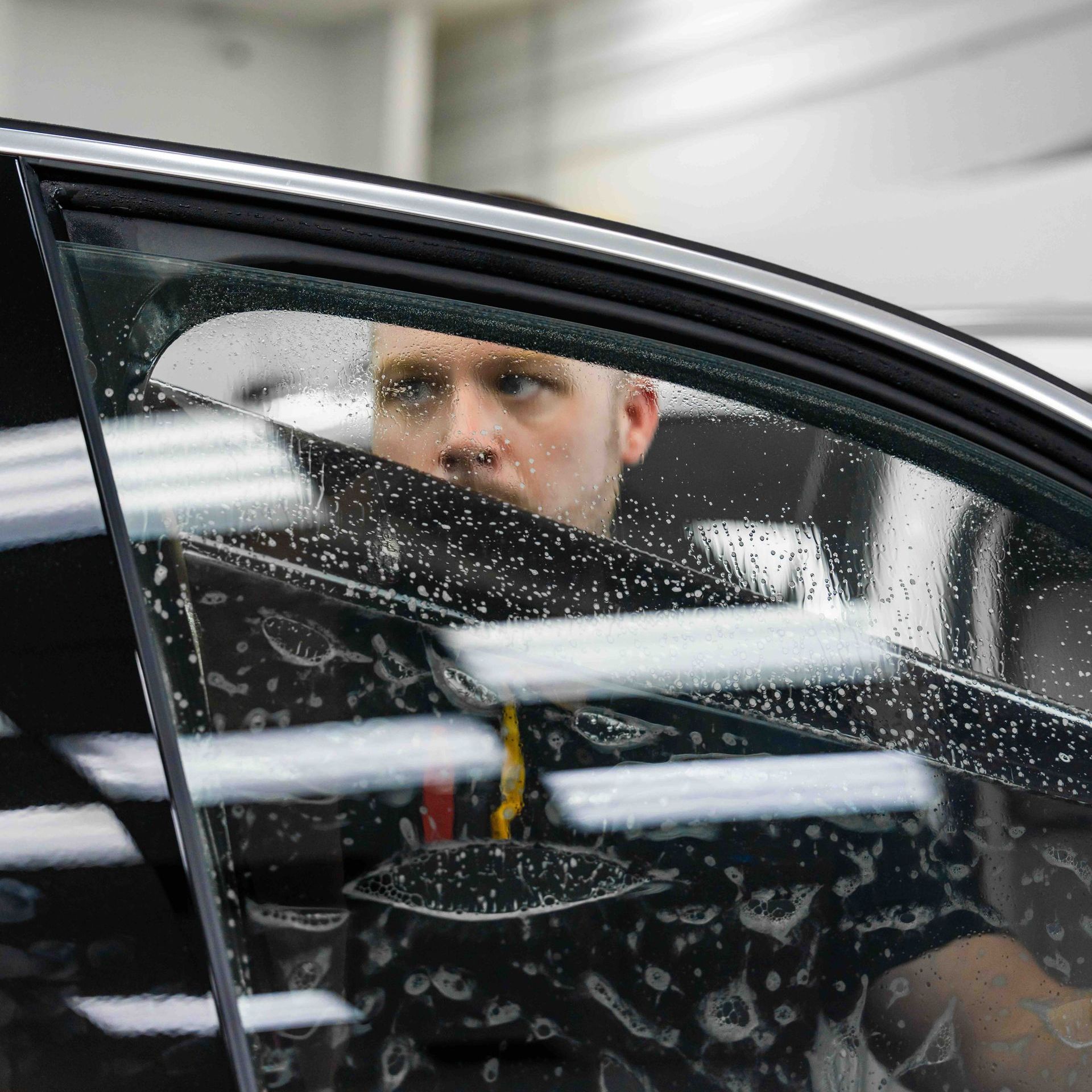 A man is sitting in a car looking out the window.