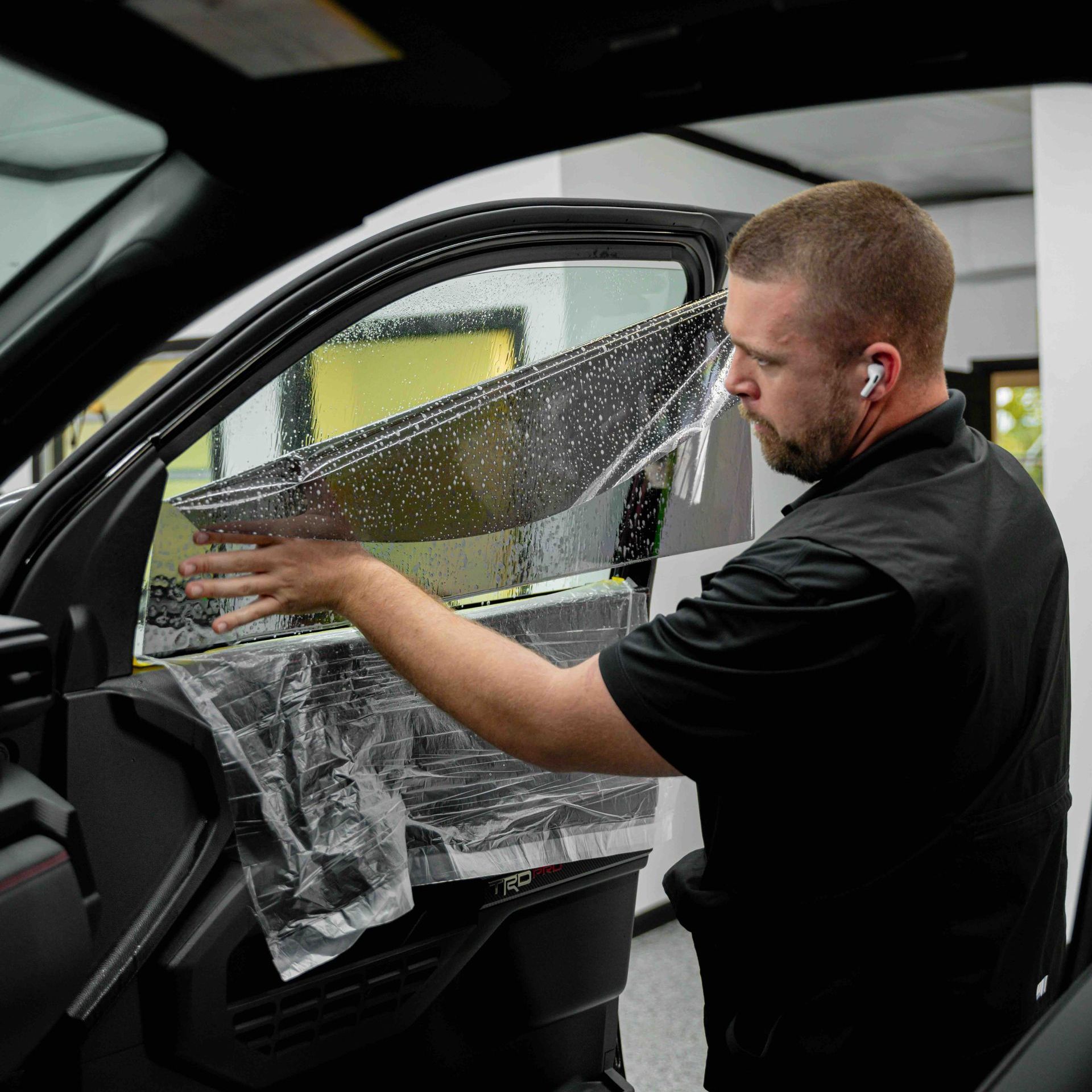 A man is putting a film on the window of a car.