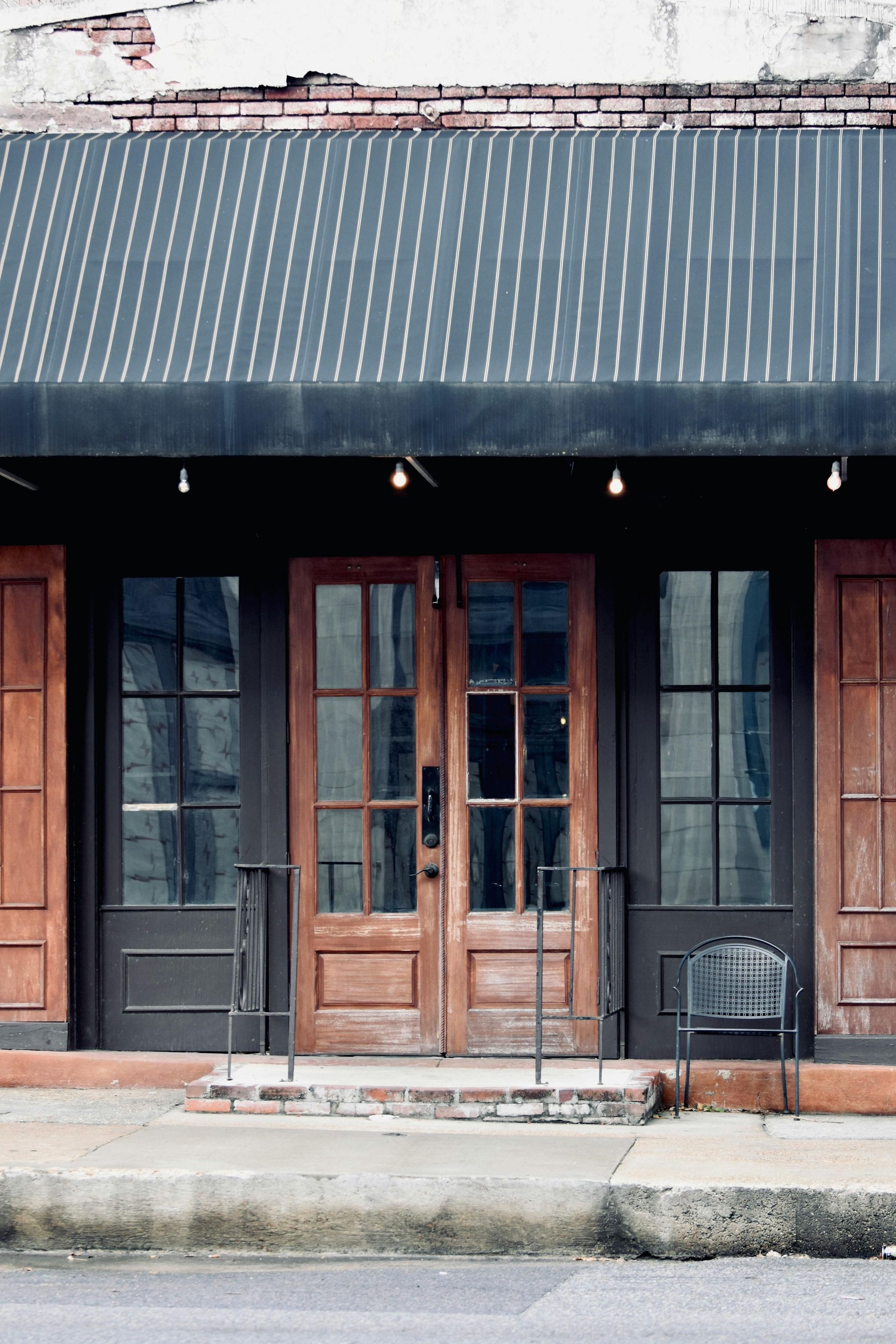 The front of a building with wooden doors and a black awning.