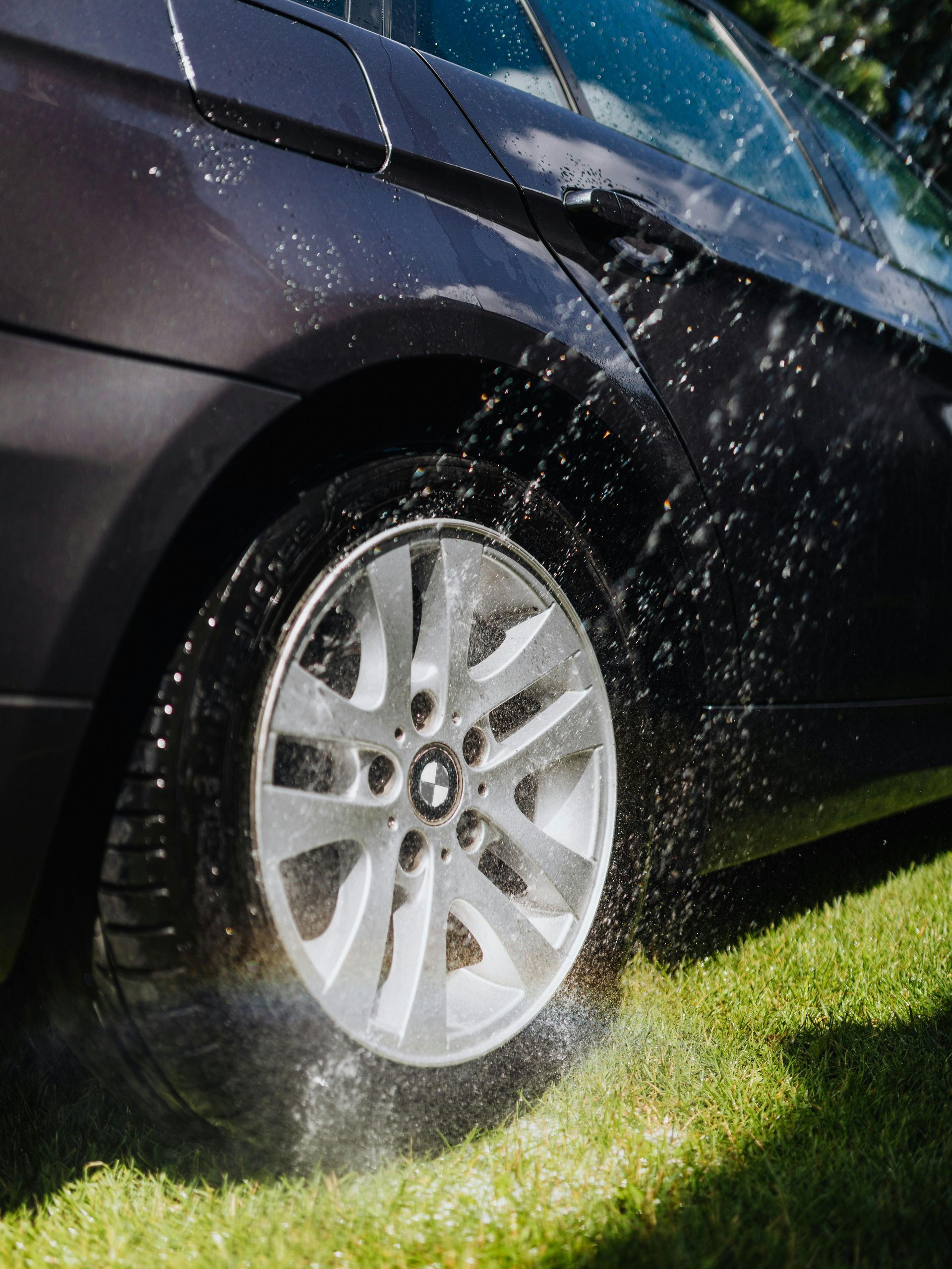 A car is being sprayed with water on the grass.