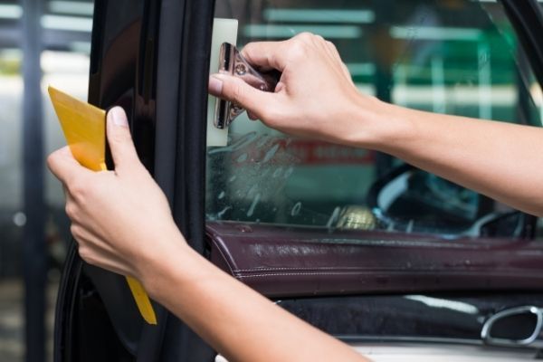 A person is applying window tinting to a car window.