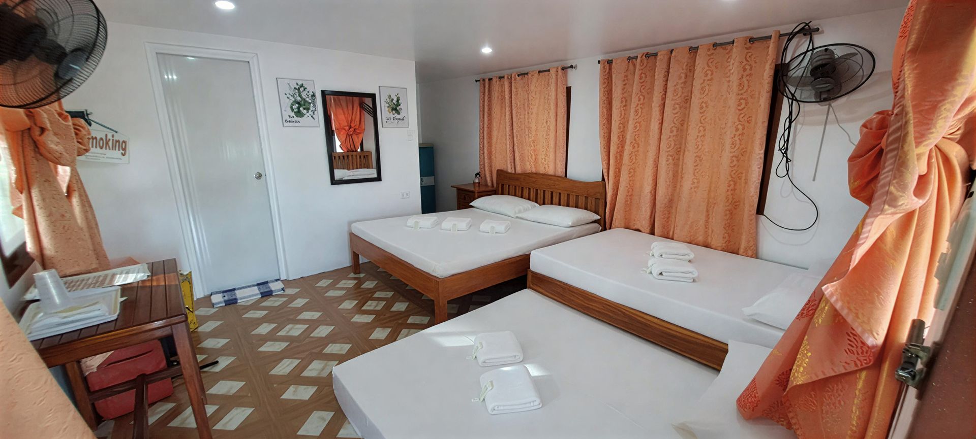 Bedroom with three beds, orange curtains, and a ceiling fan.